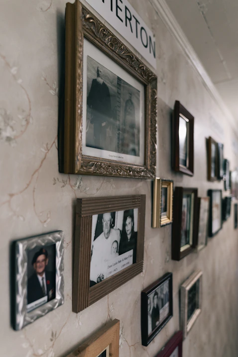 Numerous framed photographs adorn a patterned wall in a hallway