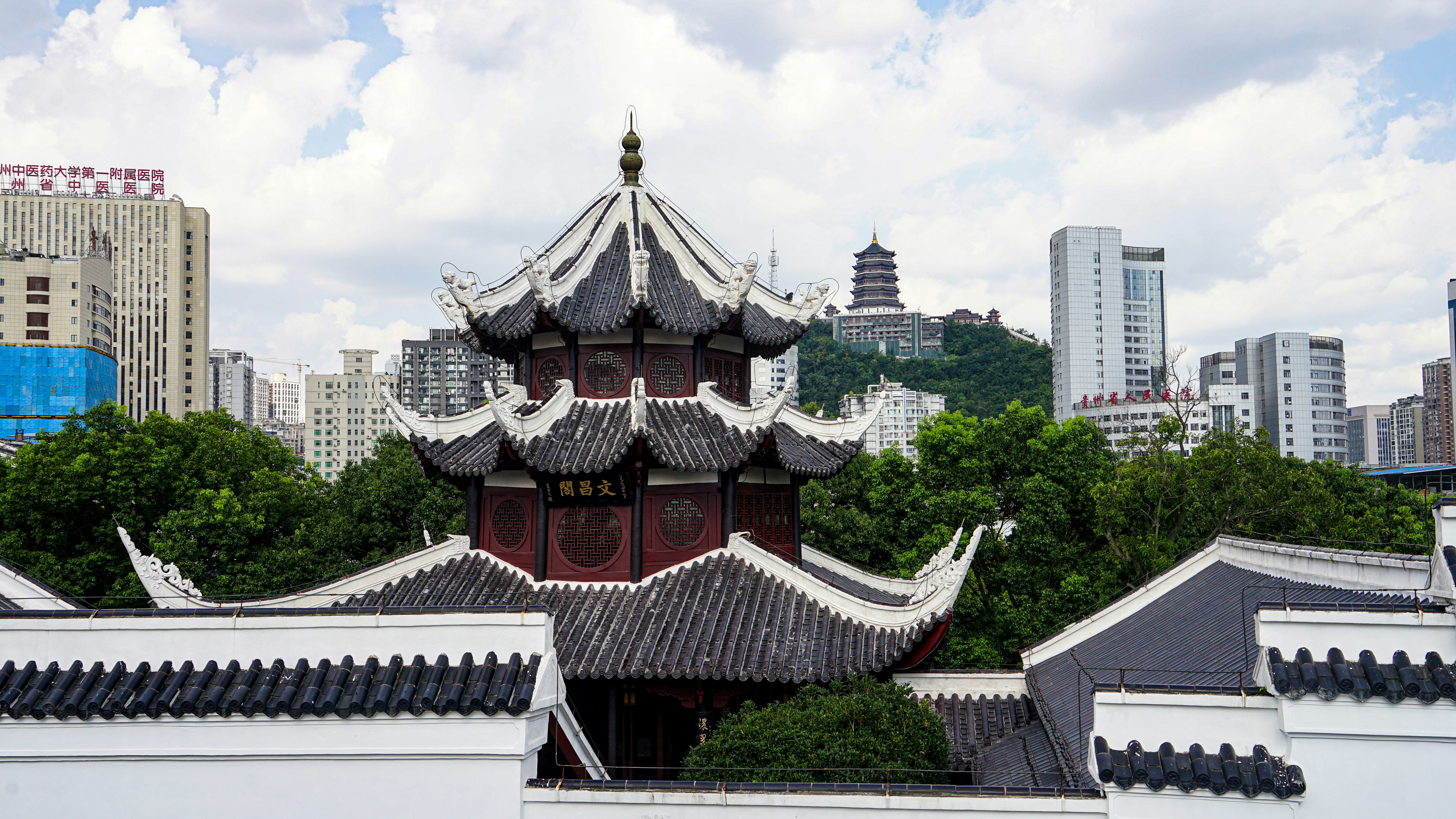 Pagoda tradicional china entre edificios modernos de la ciudad y árboles.