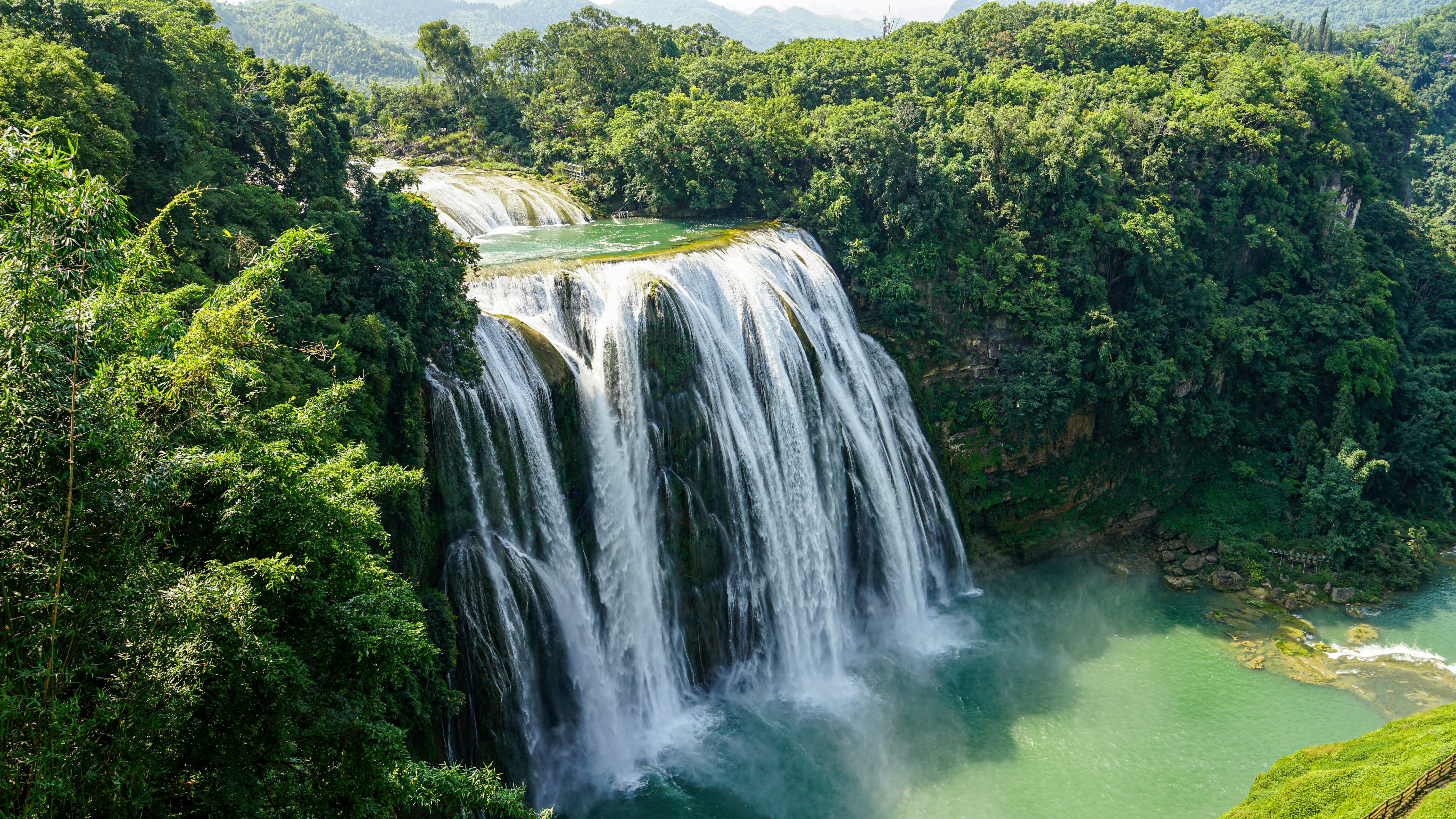 Majestuosa cascada cae en una piscina turquesa entre una vegetación exuberante.