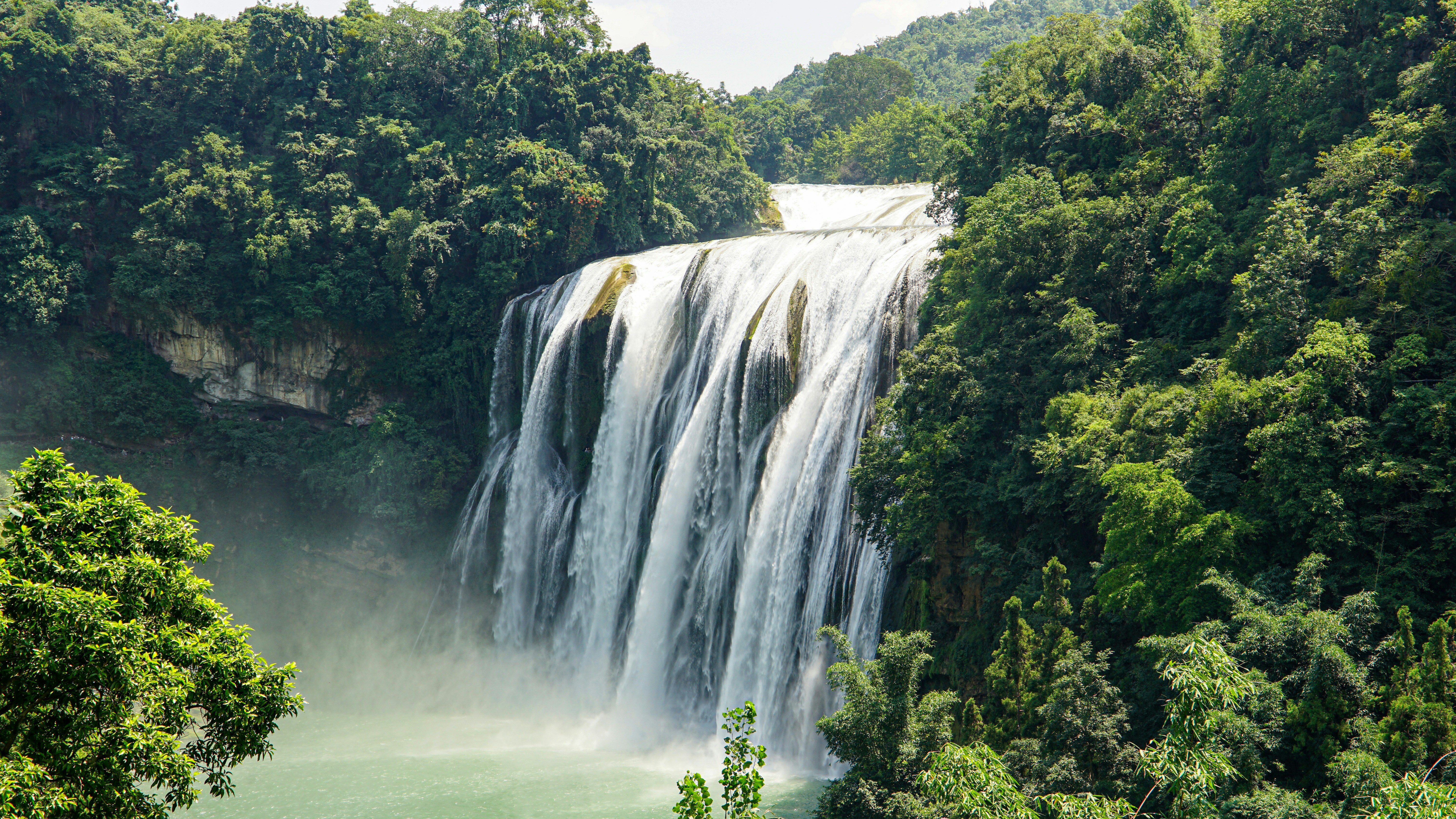 Majestuosa cascada que cae a través de un frondoso bosque verde.