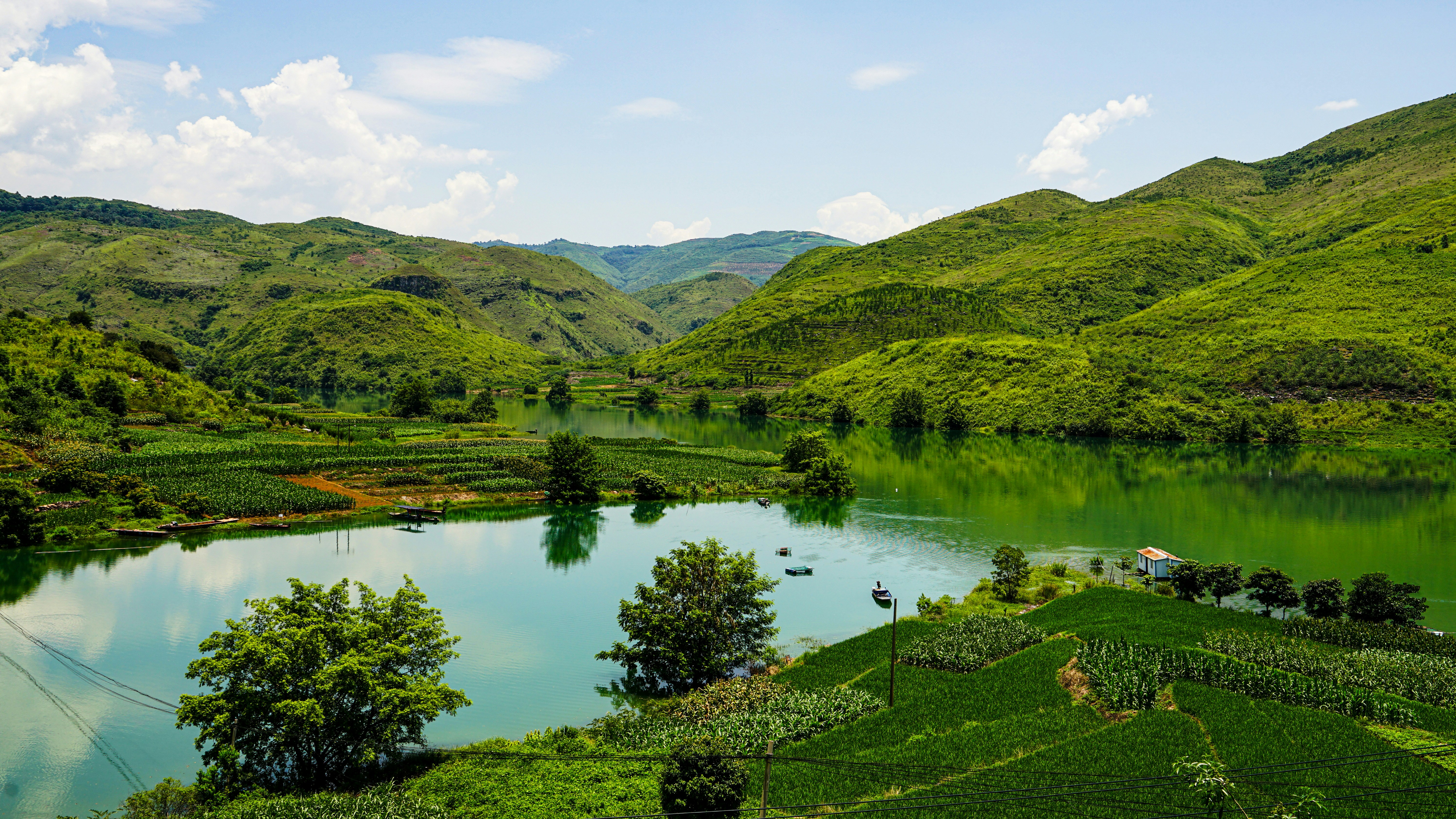 Montañas verdes rodean un lago sereno bajo un cielo azul.