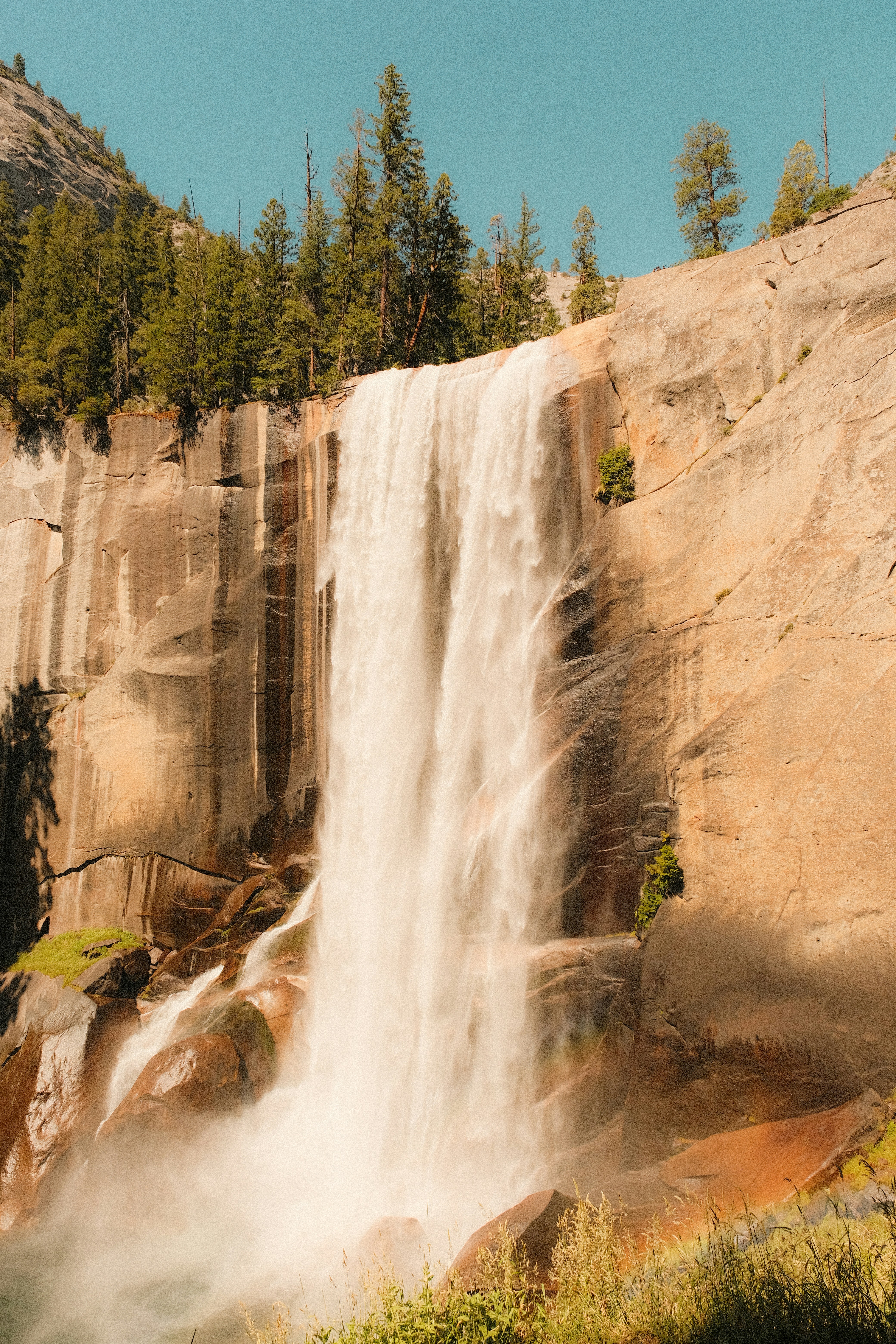 A powerful waterfall cascades down a rocky cliff with trees. - 相关推荐