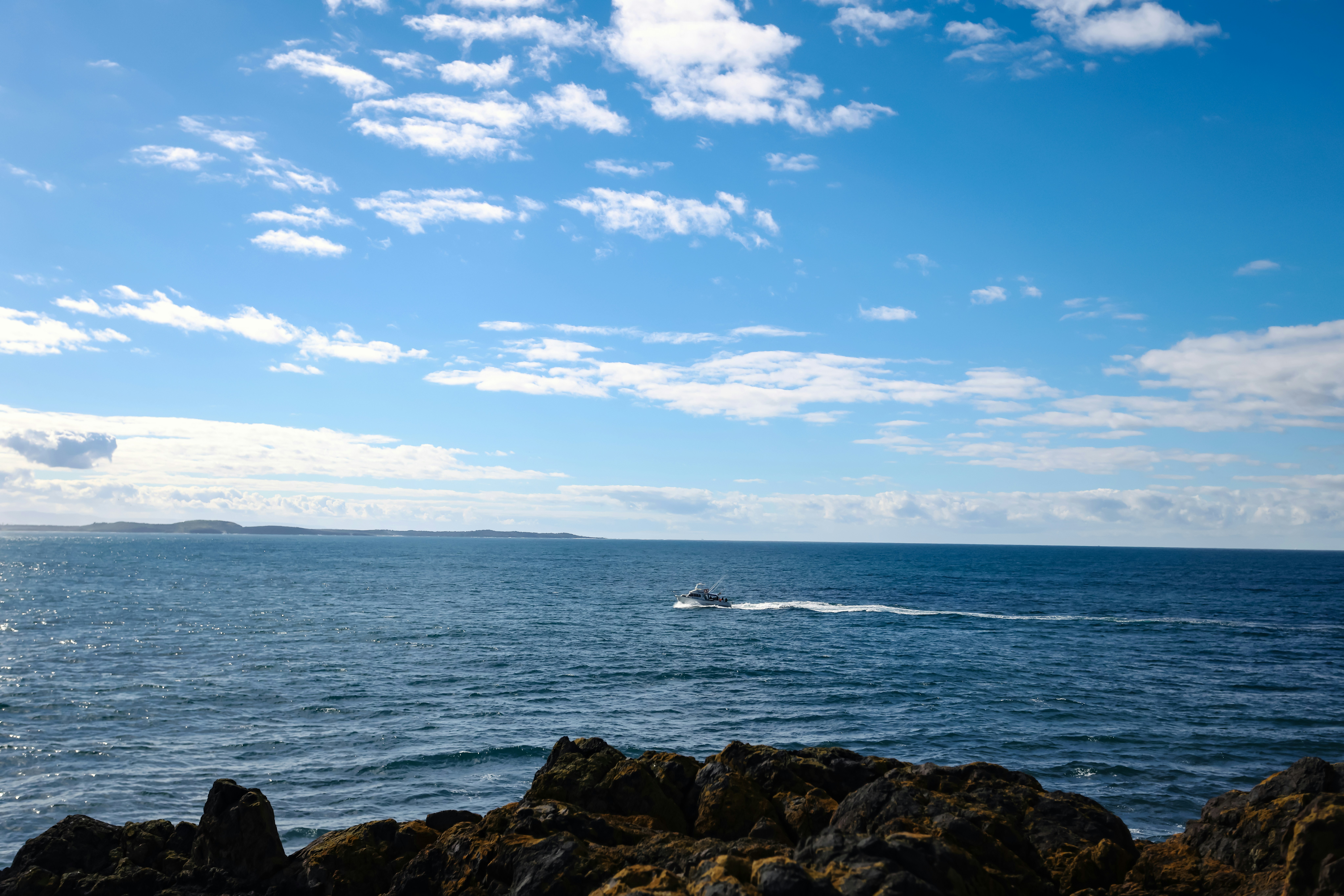 Un bateau traverse l’océan sous un ciel bleu.
