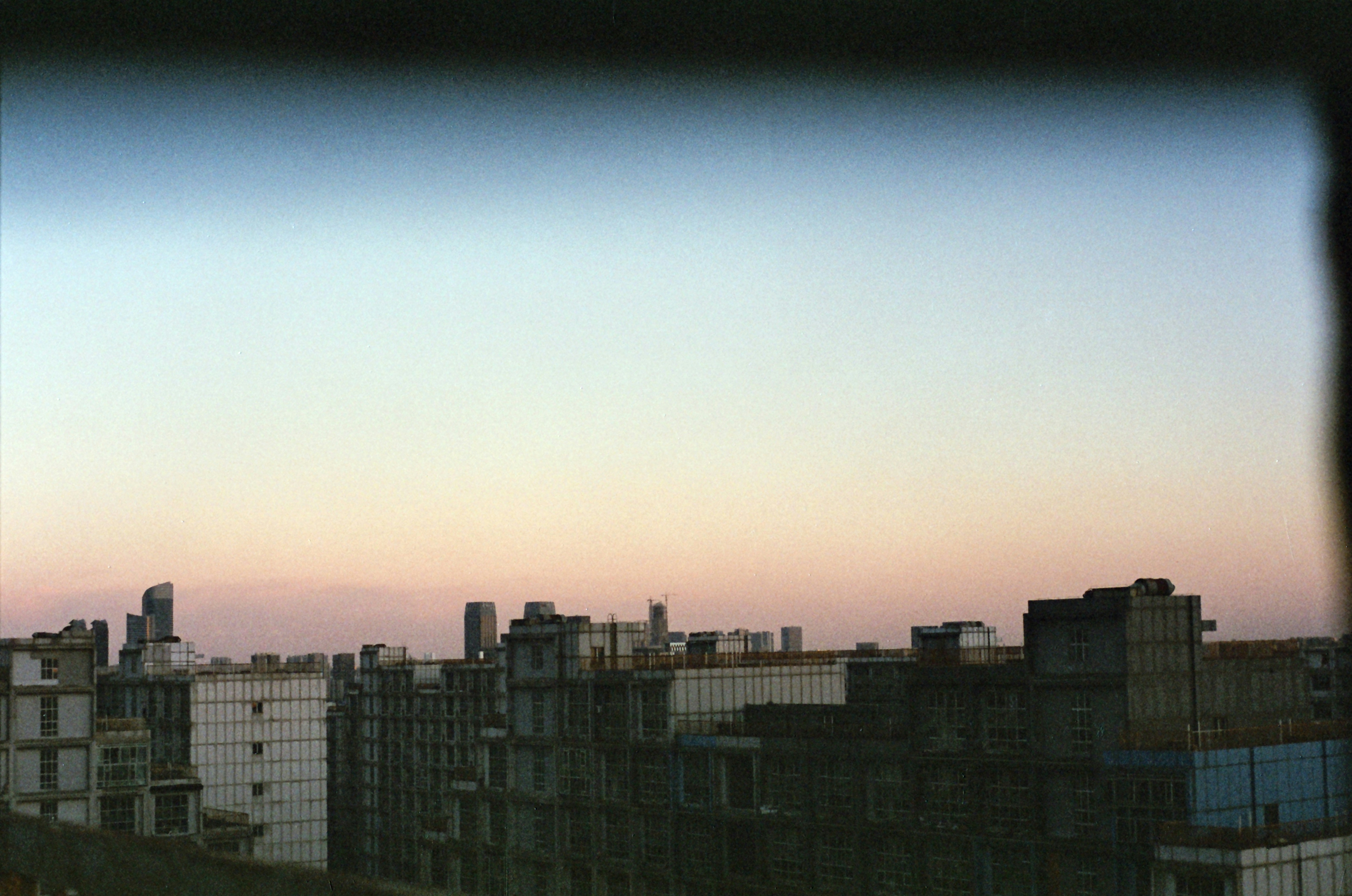 Cityscape at dusk with a gradient sky over dark buildings