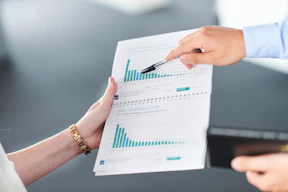 Two people analyzing a document with green bar charts