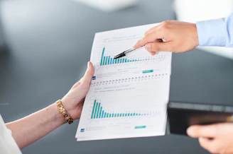Two people analyzing a document with green bar charts.