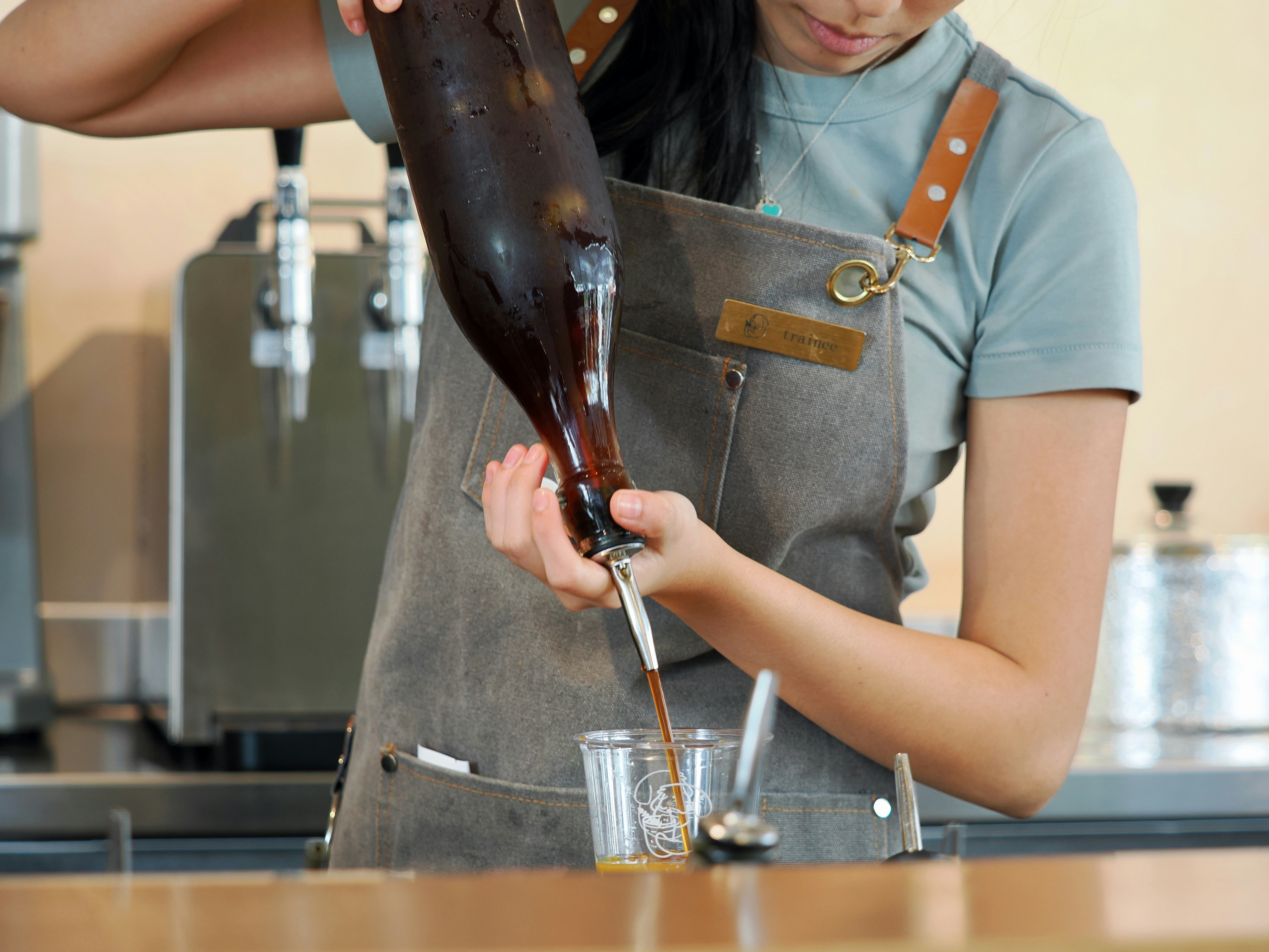 Barista in an apron pouring from a tap