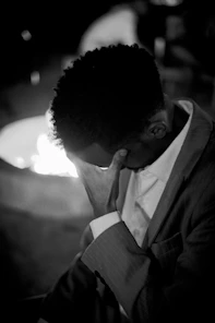 A man with his head bowed, hand on face
