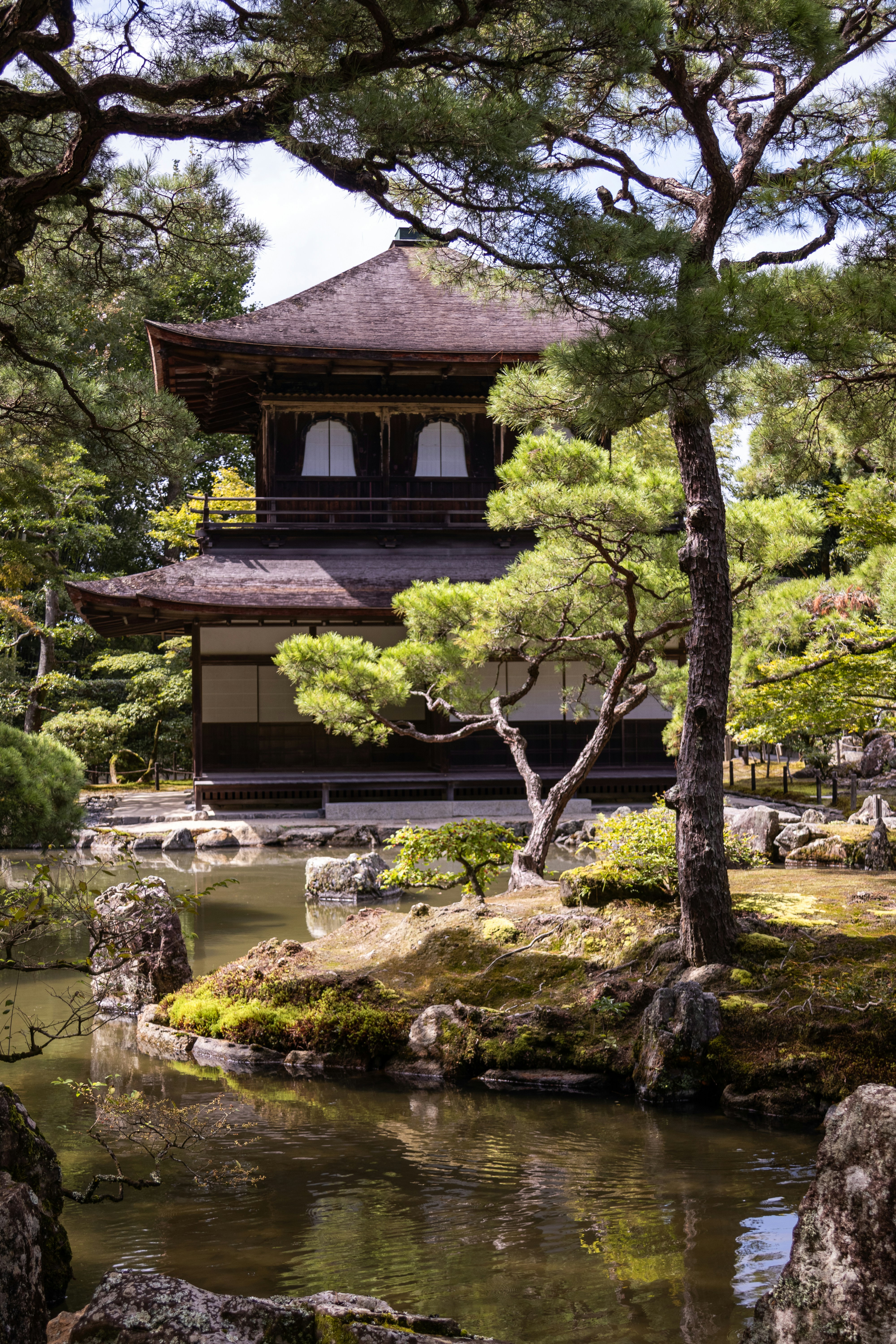Traditional japanese temple by a serene pond with lush trees