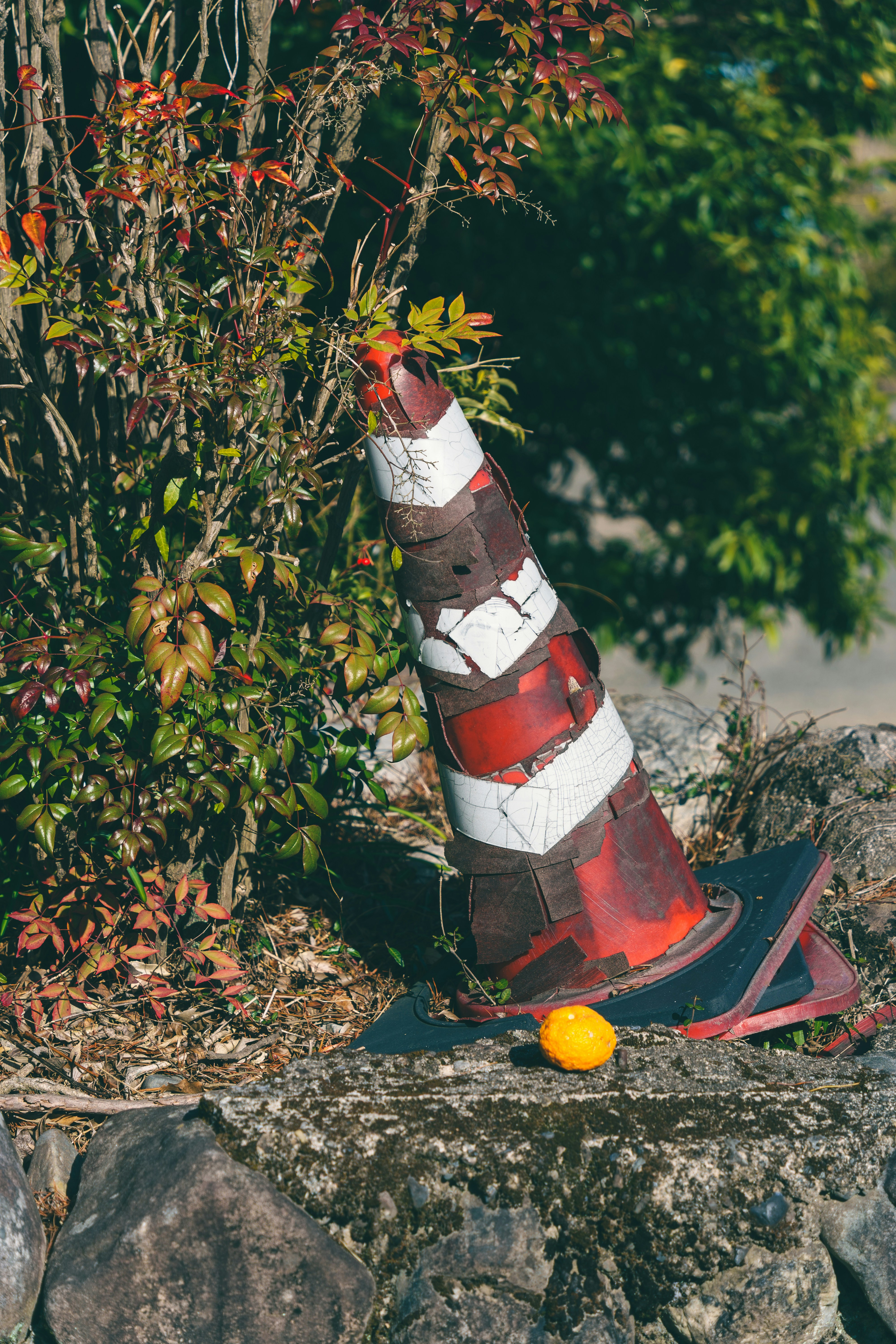 Old traffic cone and orange fruit on stone wall.