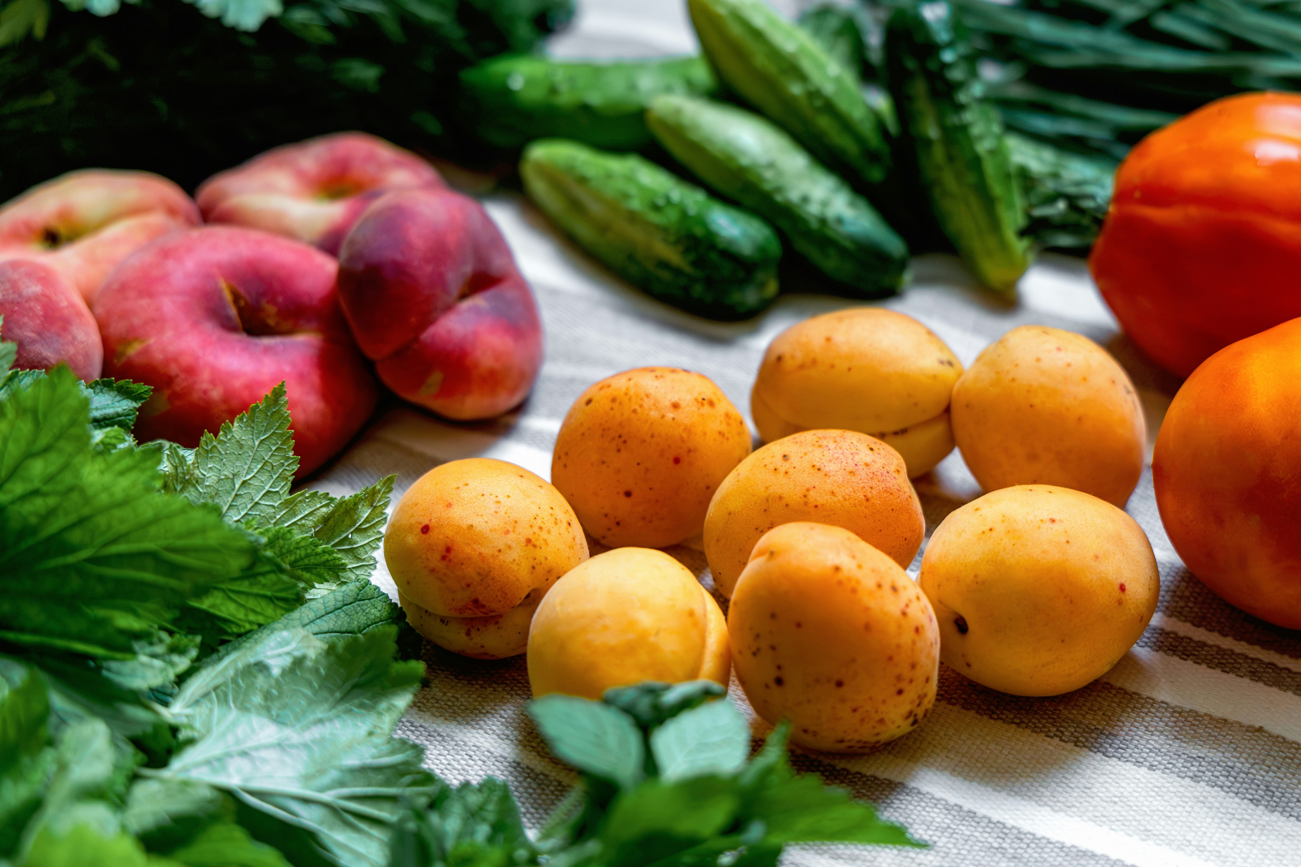 Fresh peaches, apricots, cucumbers, tomatoes, and leafy greens.