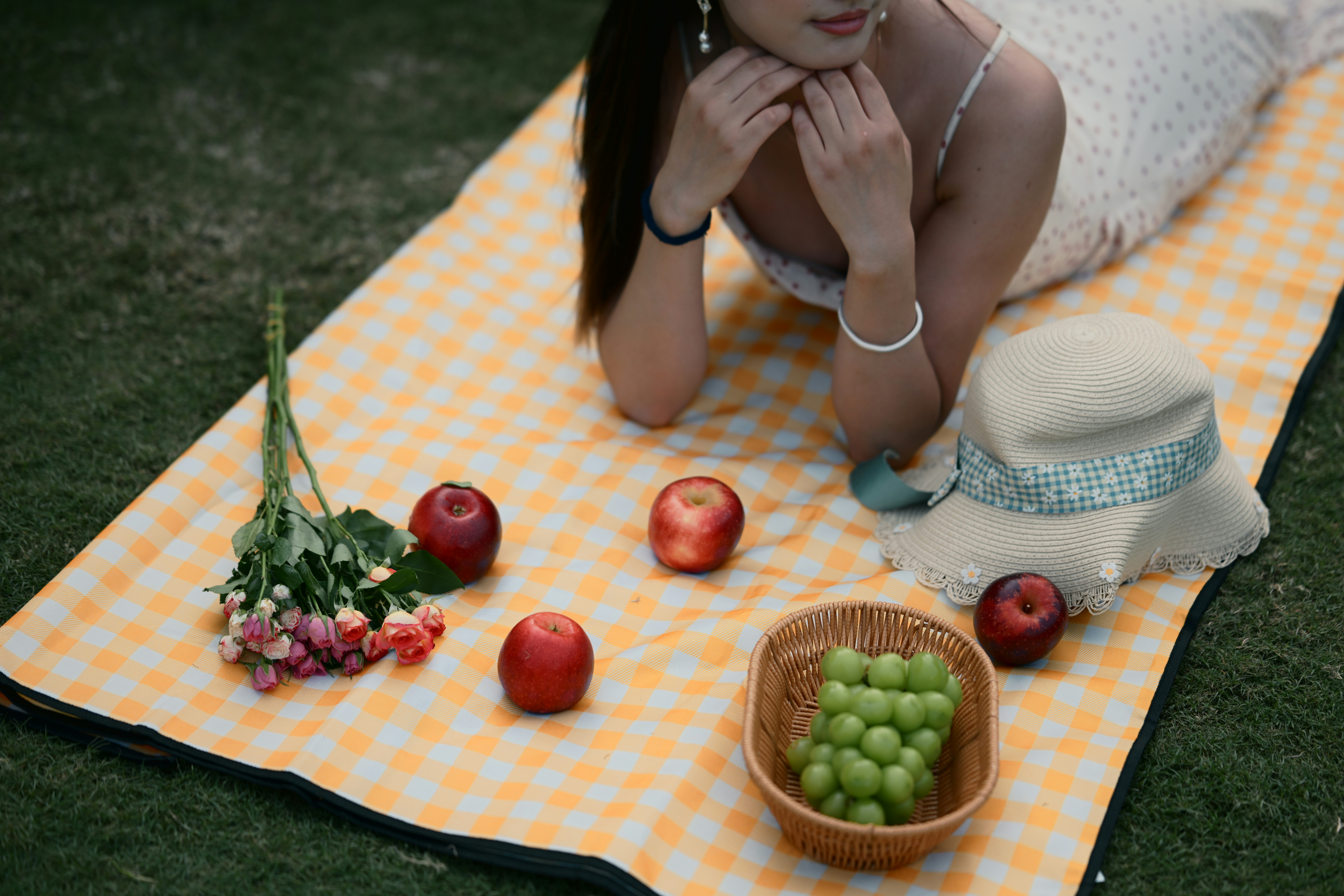 Woman lying on an orange gingham blanket with apples