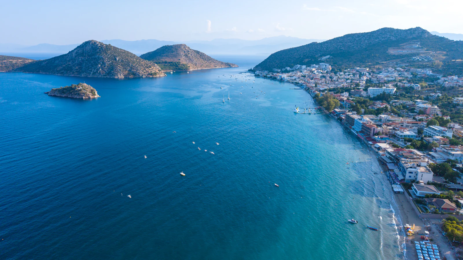 A Mediterranean bay seen from above, boats moored along the shoreline