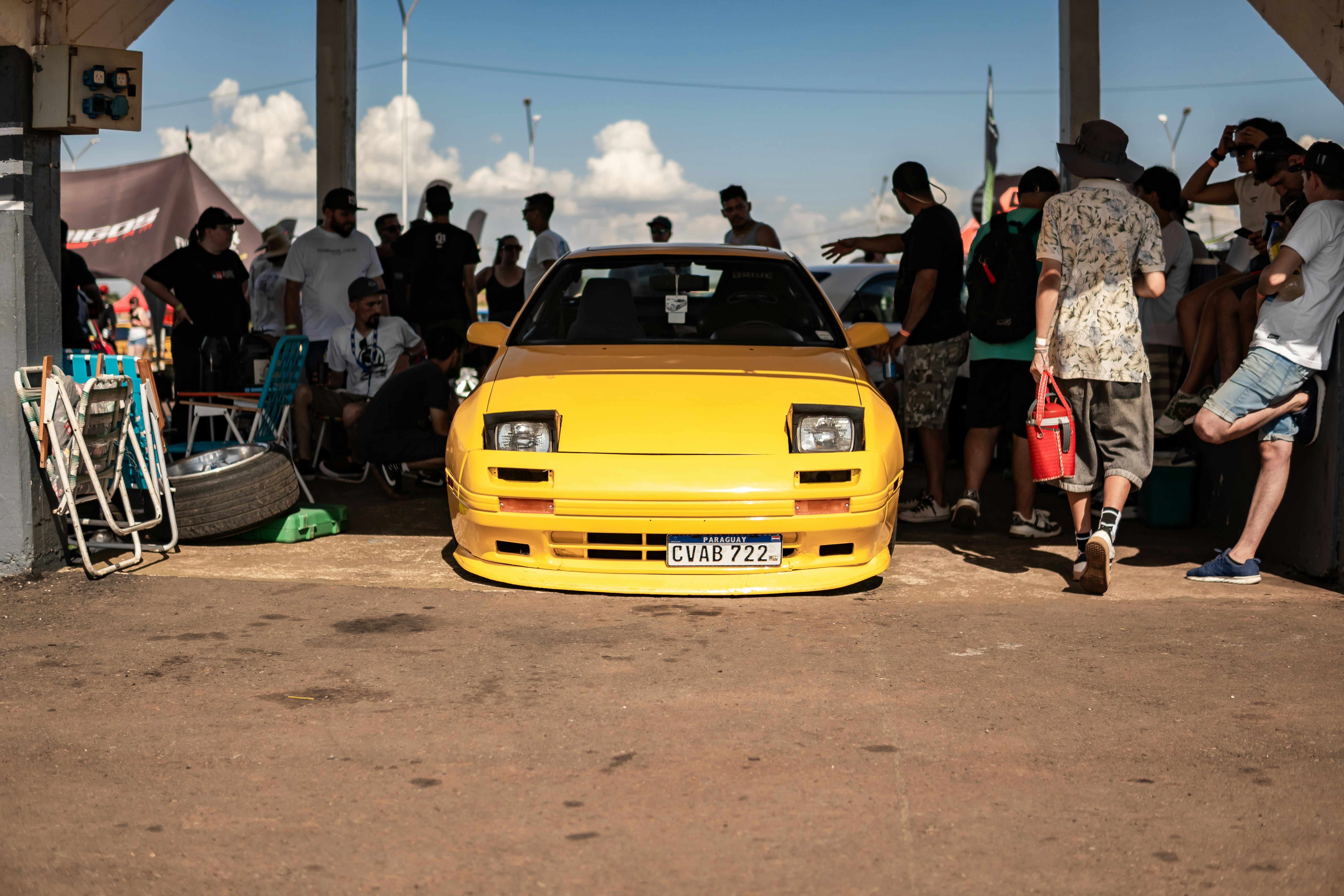 Um carro amarelo brilhante estacionado entre uma multidão de pessoas.