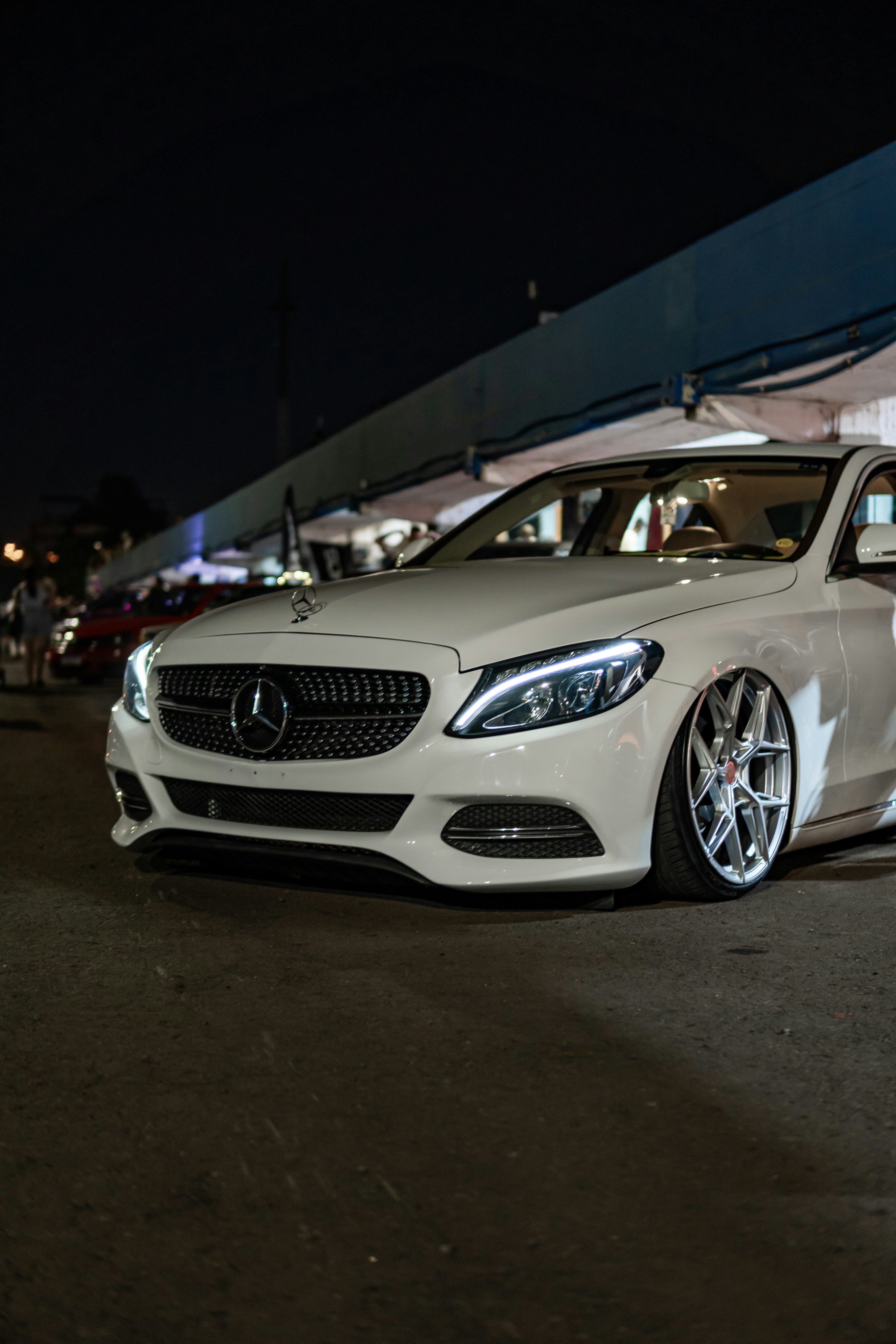 Carro Mercedes-Benz branco estacionado à noite com rodas personalizadas.