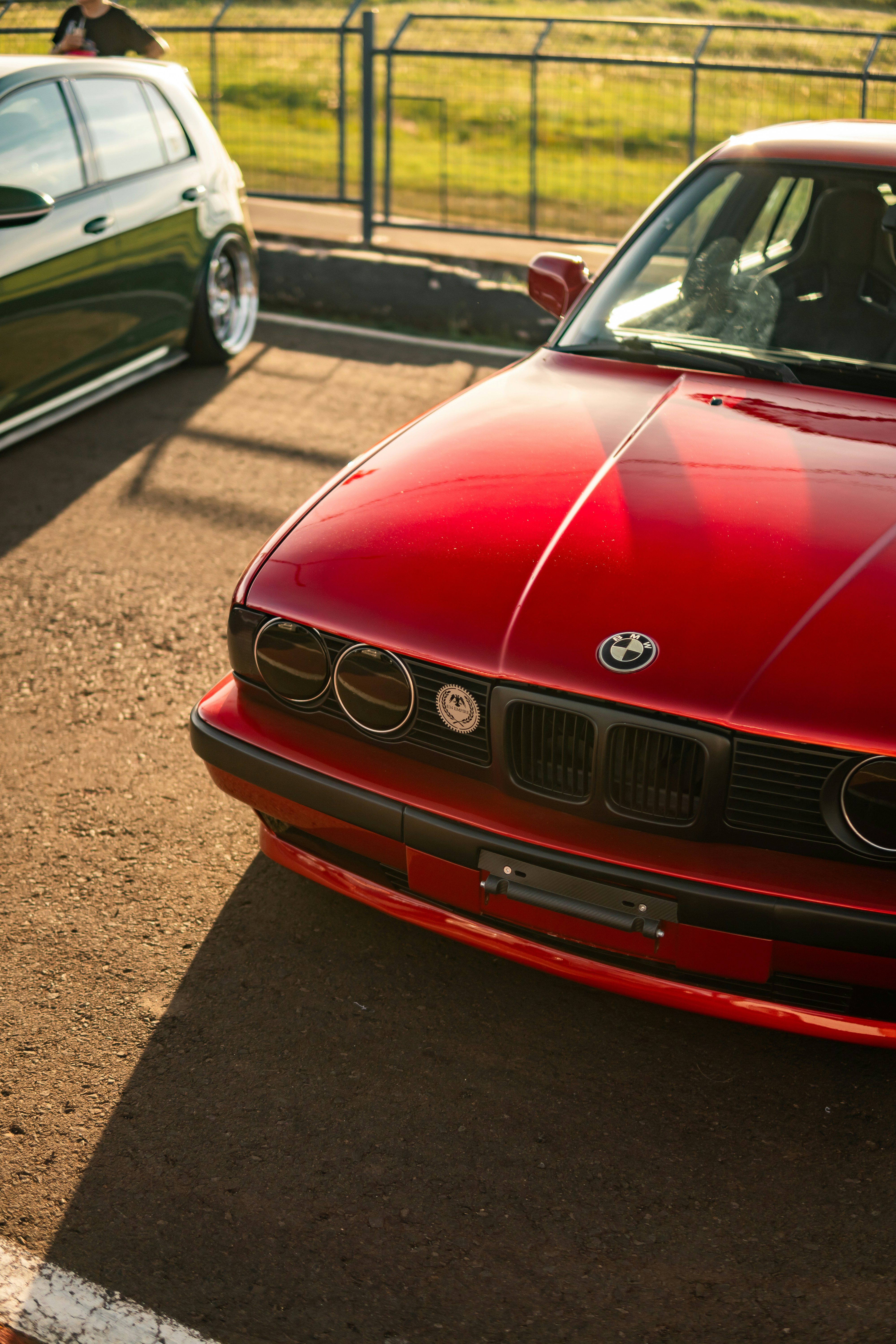 Um carro BMW vermelho estacionado em uma pista asfaltada.