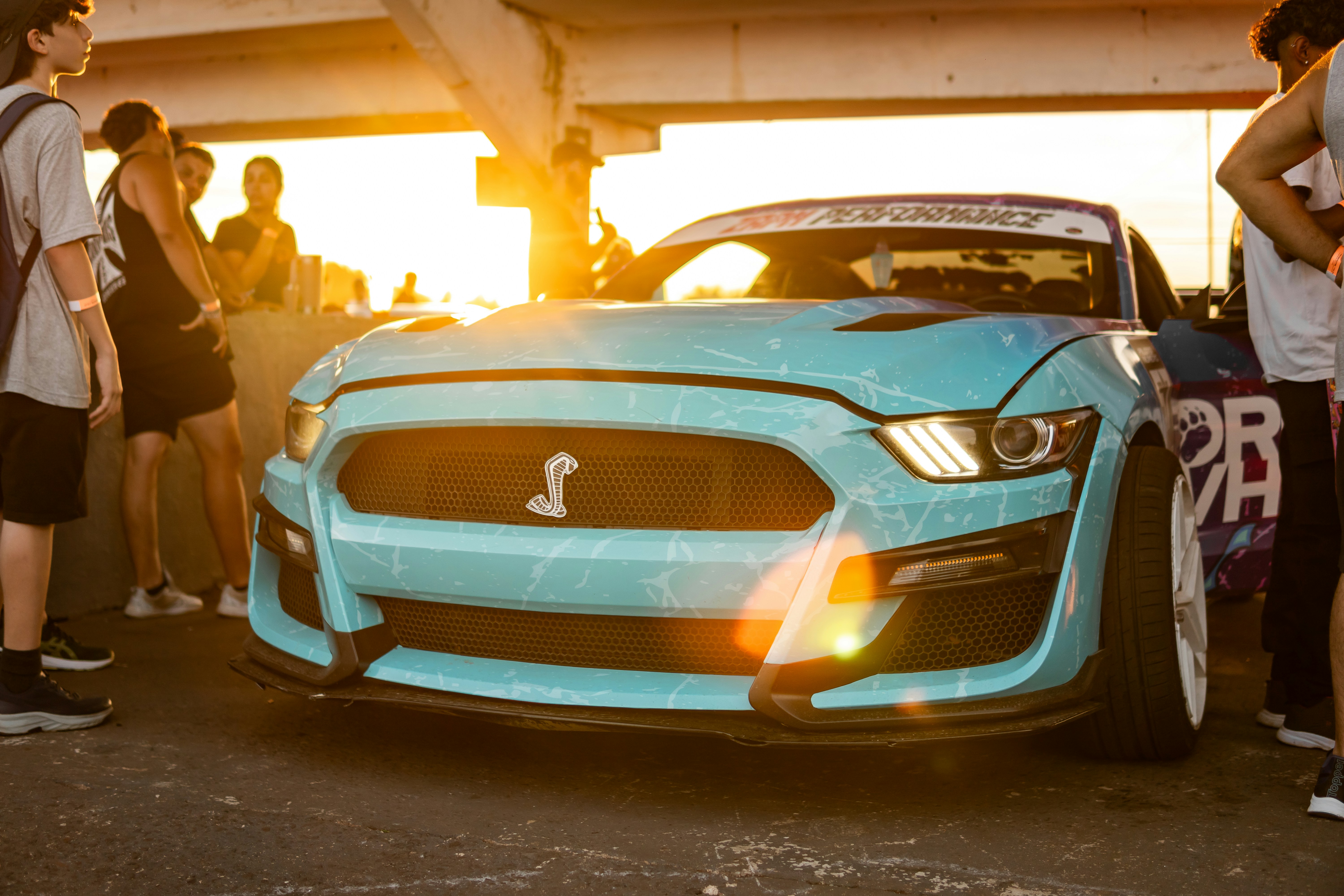 Deslumbrante carro custom blue mustang iluminado pelo sol da hora dourada.