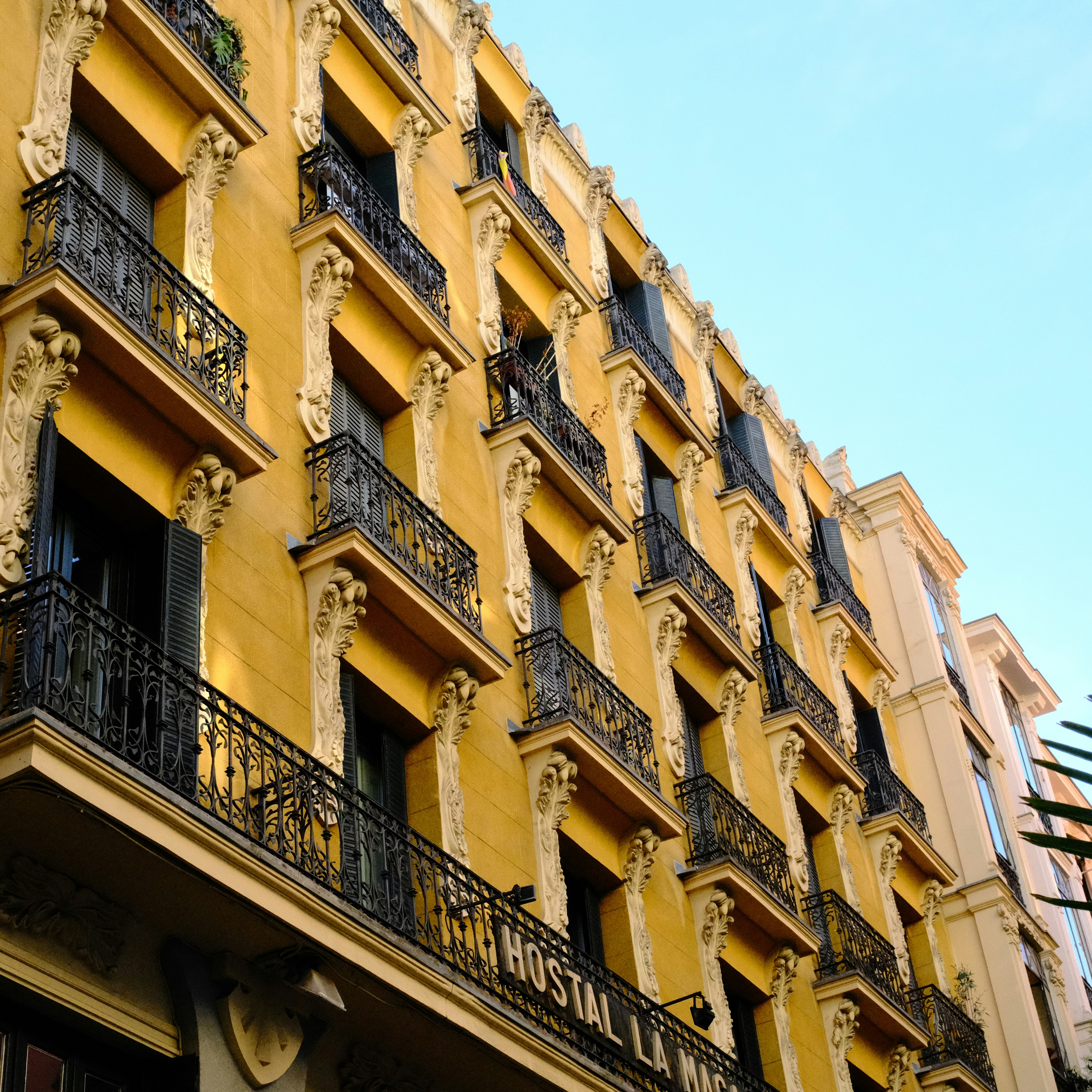 A yellow building with ornate balconies under a clear sky.