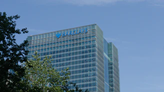 Barclays corporate building with green trees against a blue sky