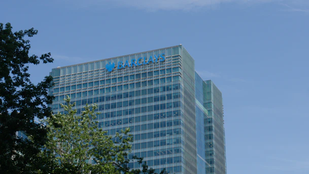 Barclays corporate building with green trees against a blue sky