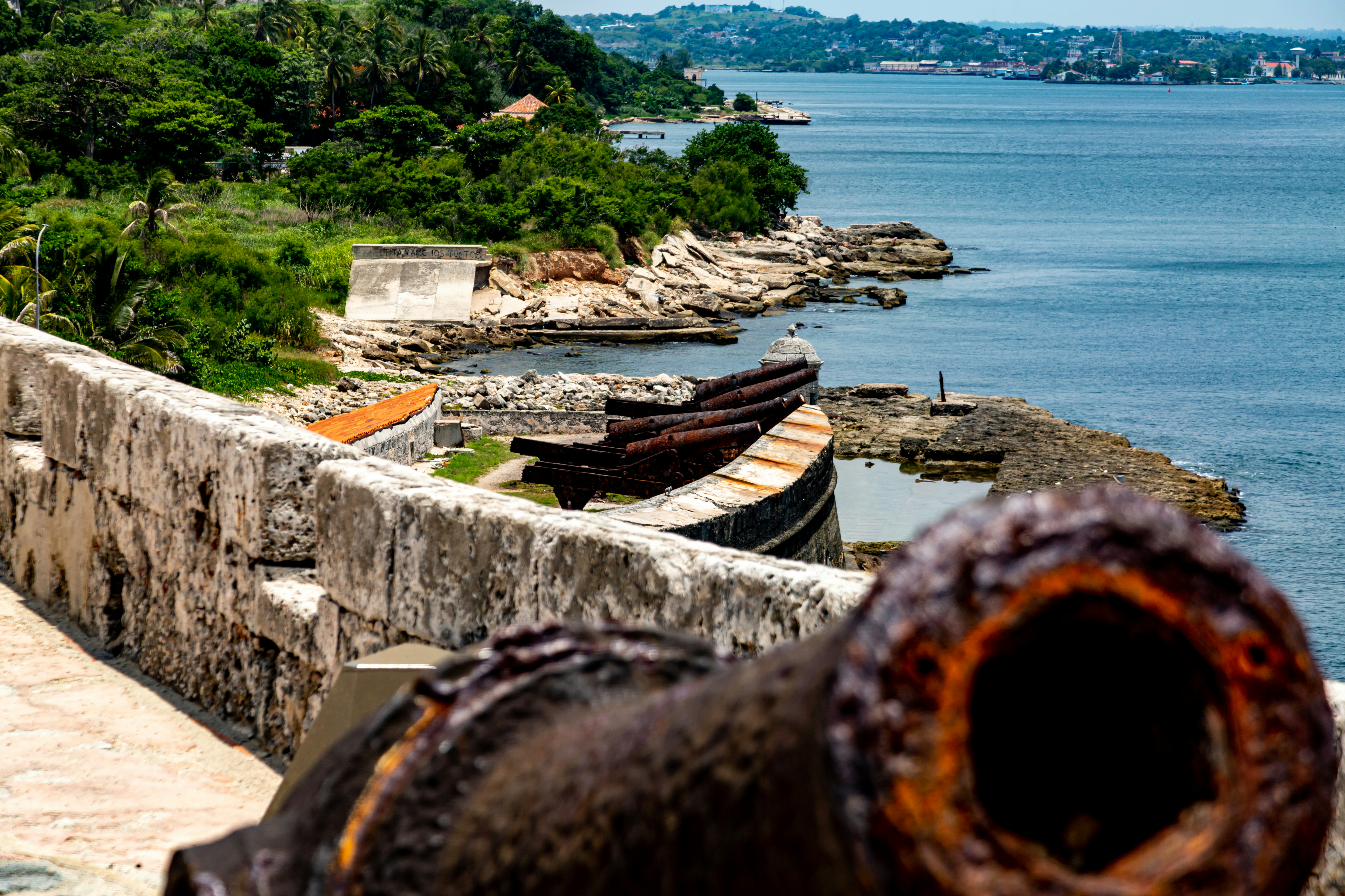 Old cannons on a stone fort overlooking a bay.