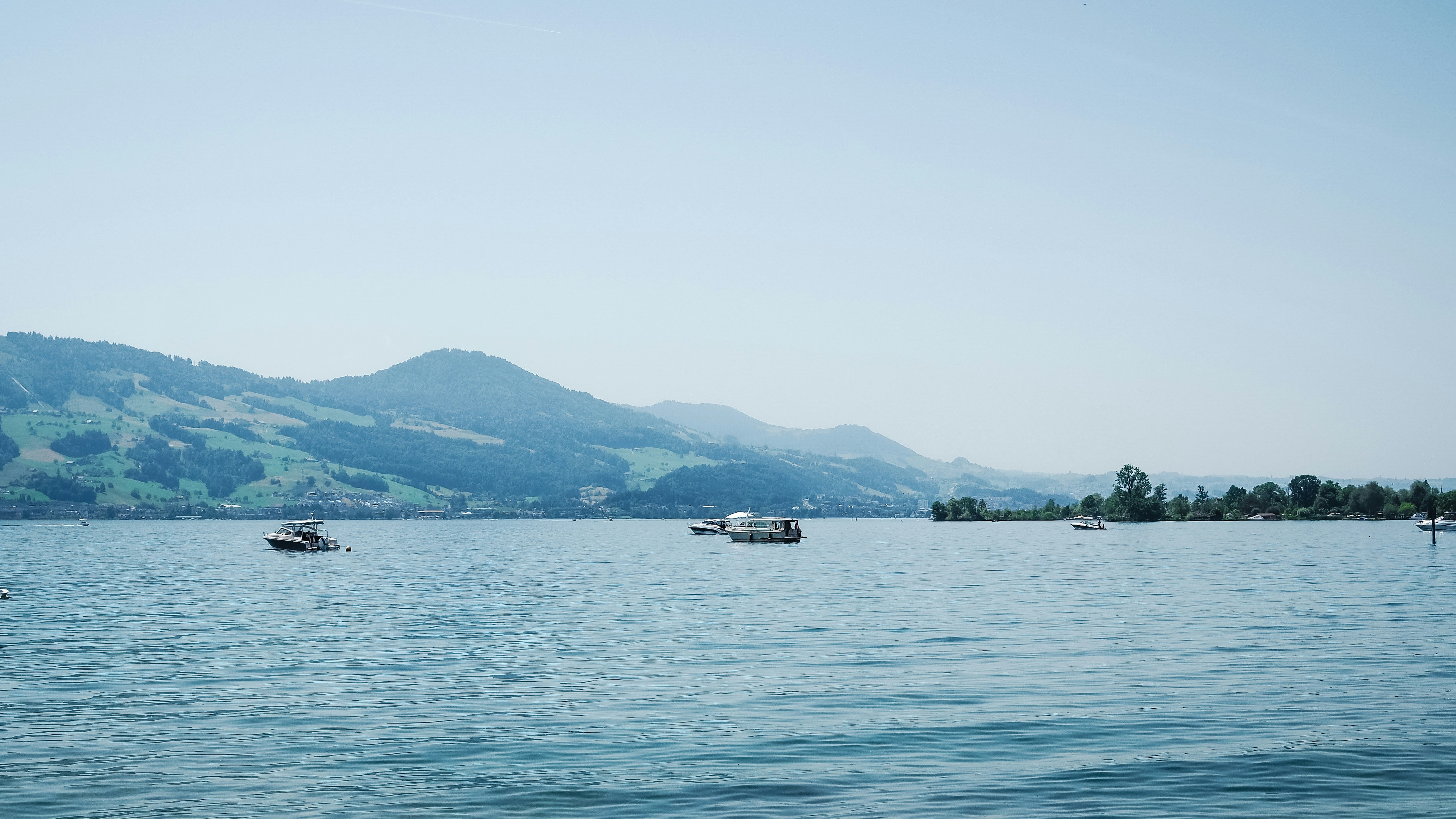 Boats on a calm lake with green mountains.