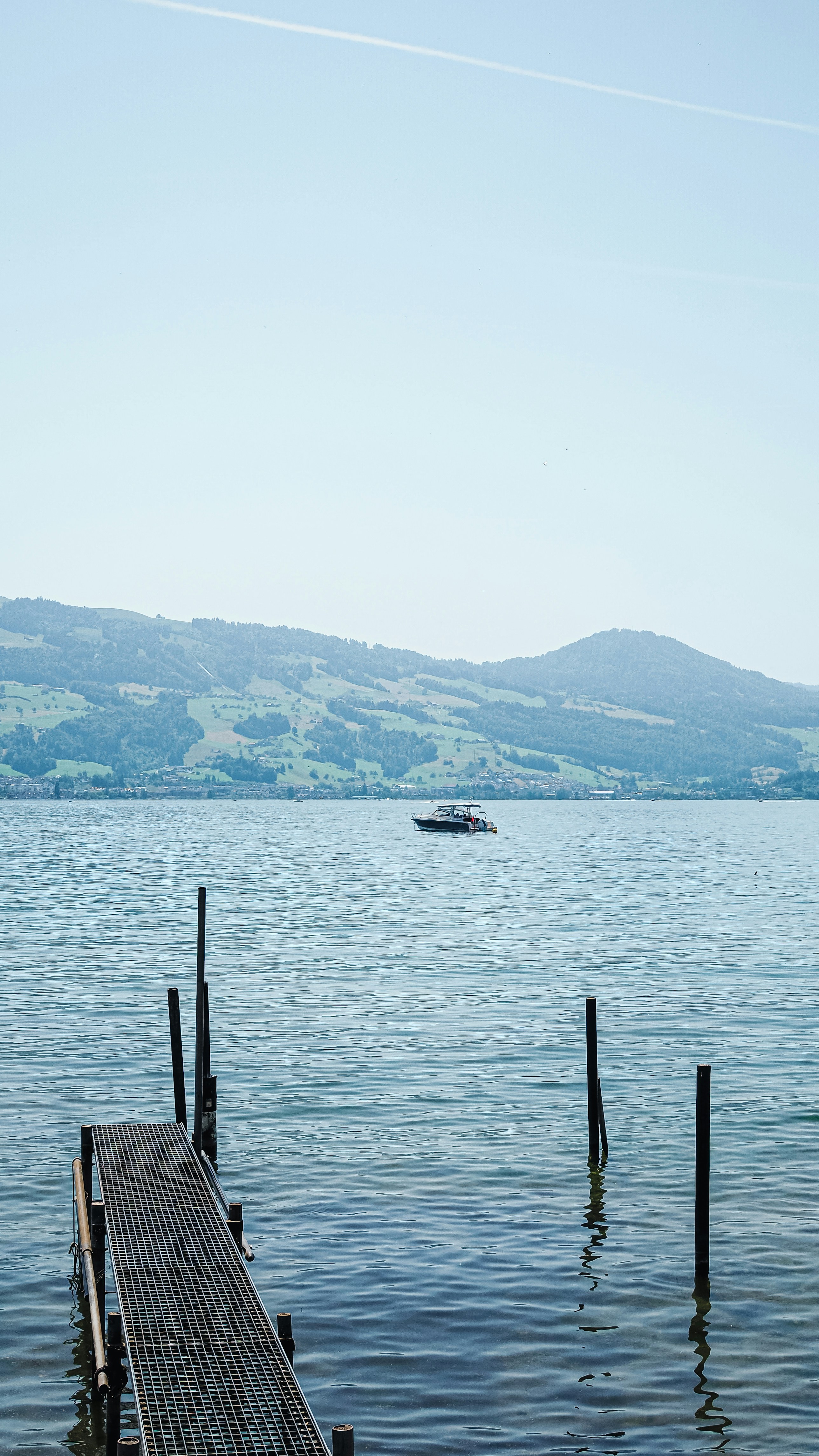 Scenic lake view with a pier, boat, and mountains.