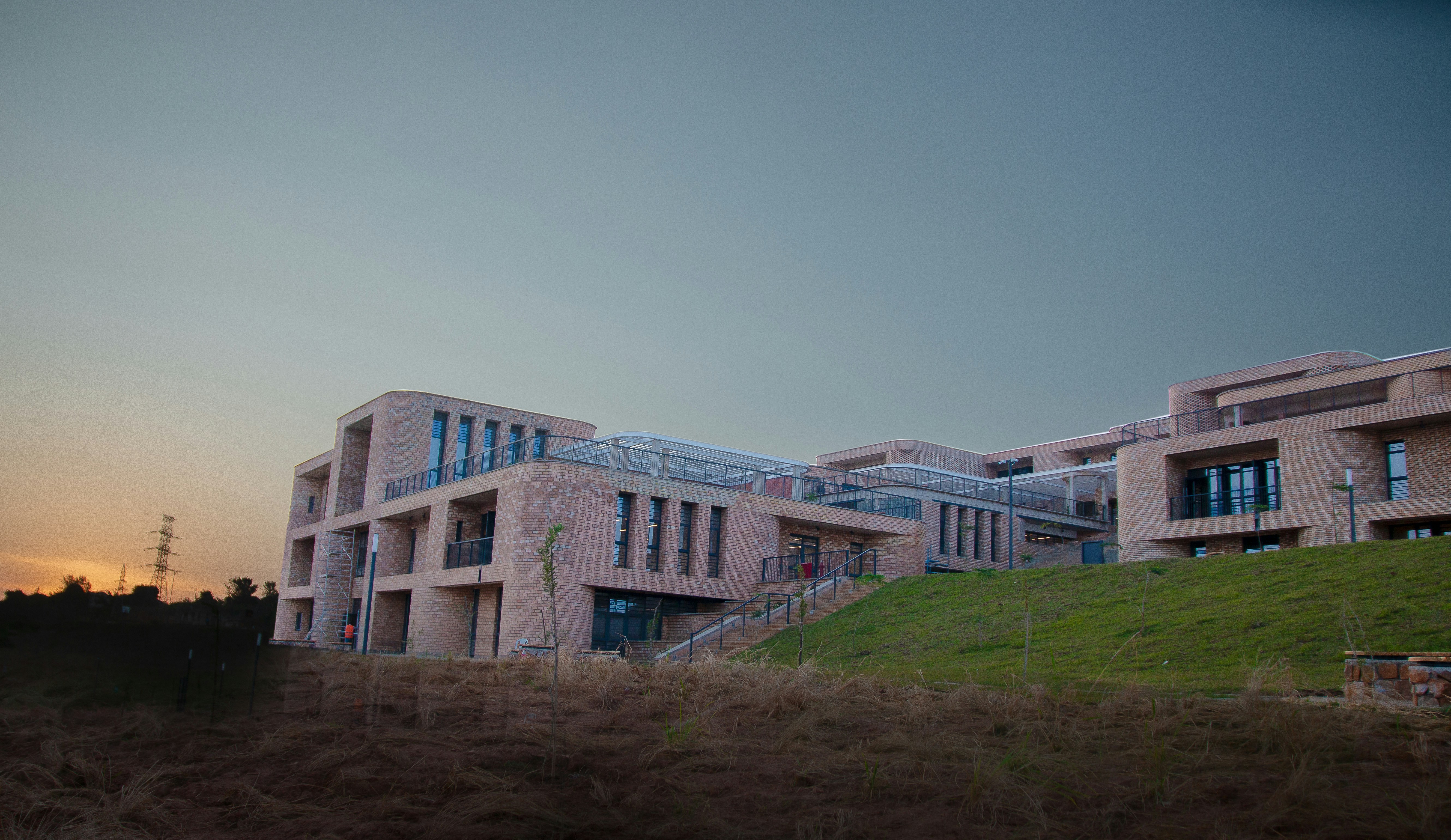 Modern building on a green hill under a twilight sky.