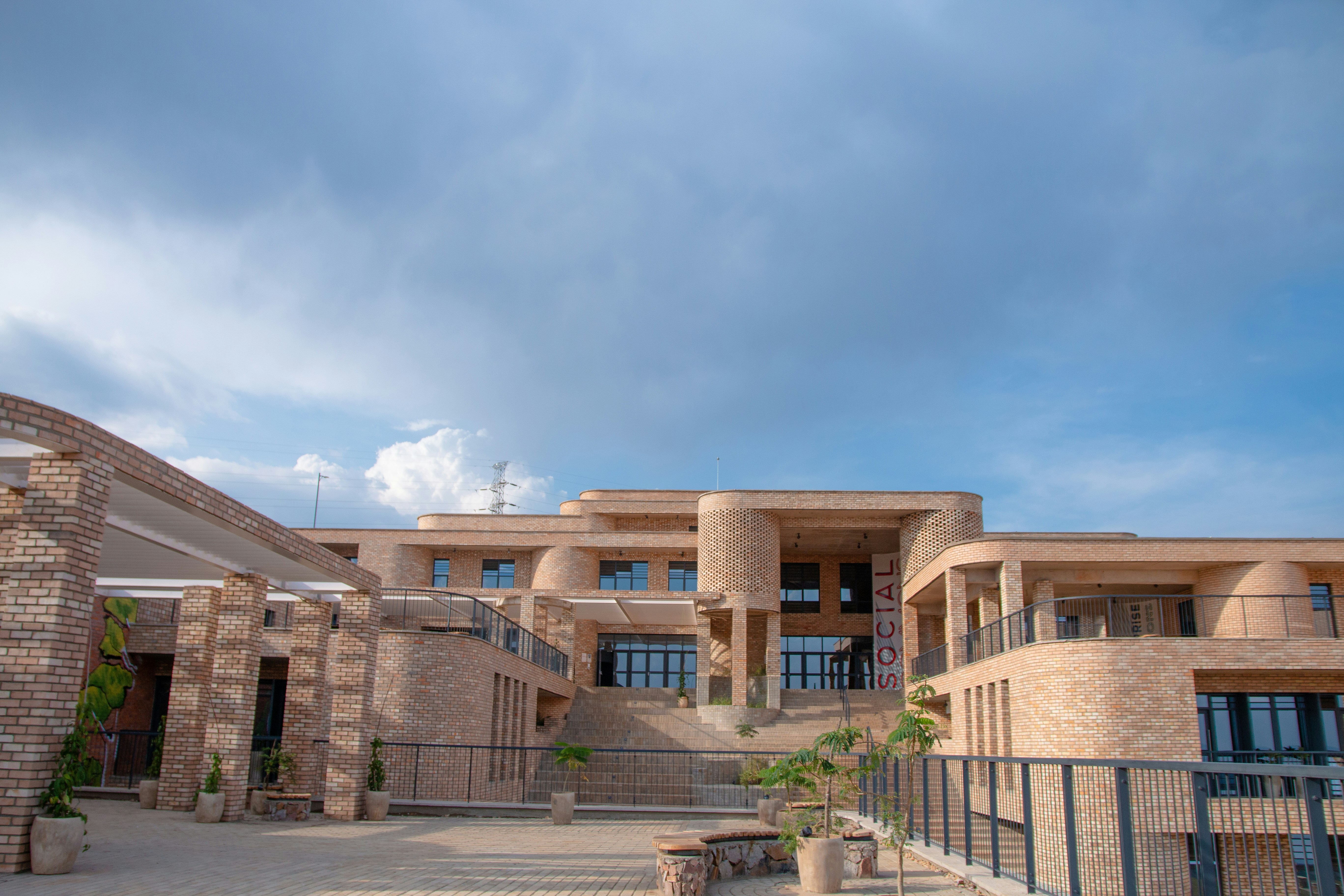 Modern brick architecture with multiple levels and a cloudy sky.