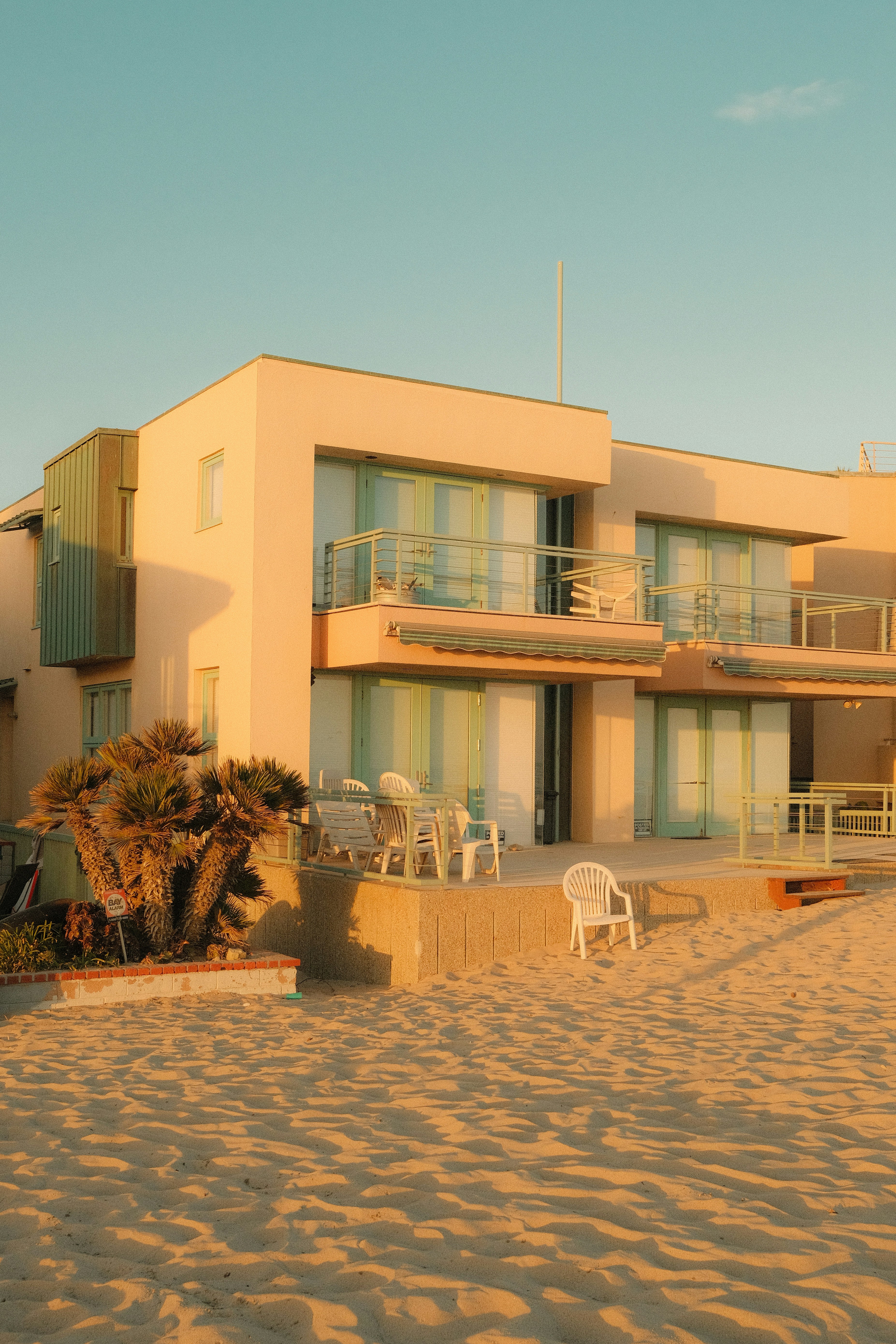 A modern building stands on a sandy beach at sunset