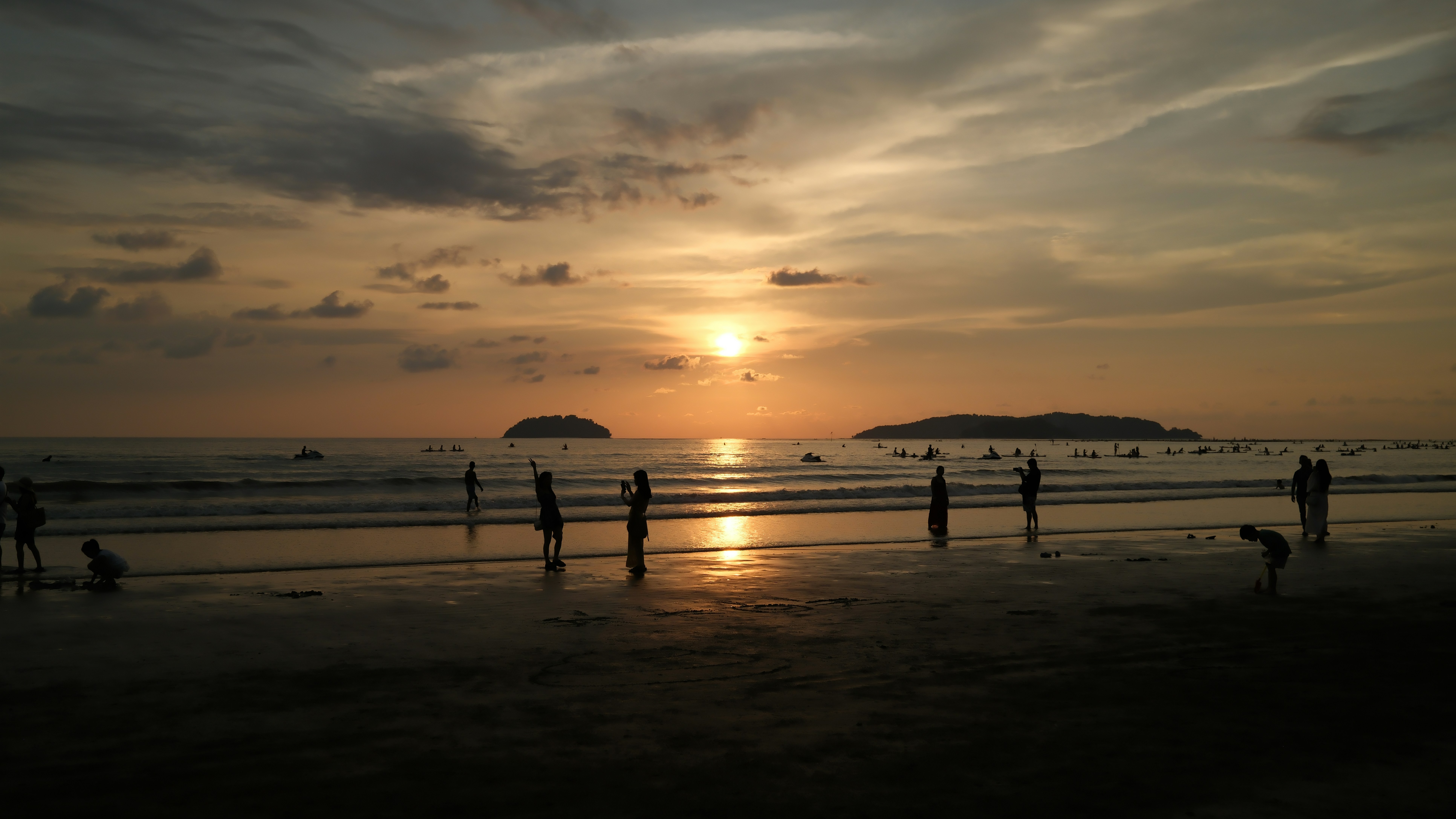 People enjoy a beautiful sunset over the ocean with islands