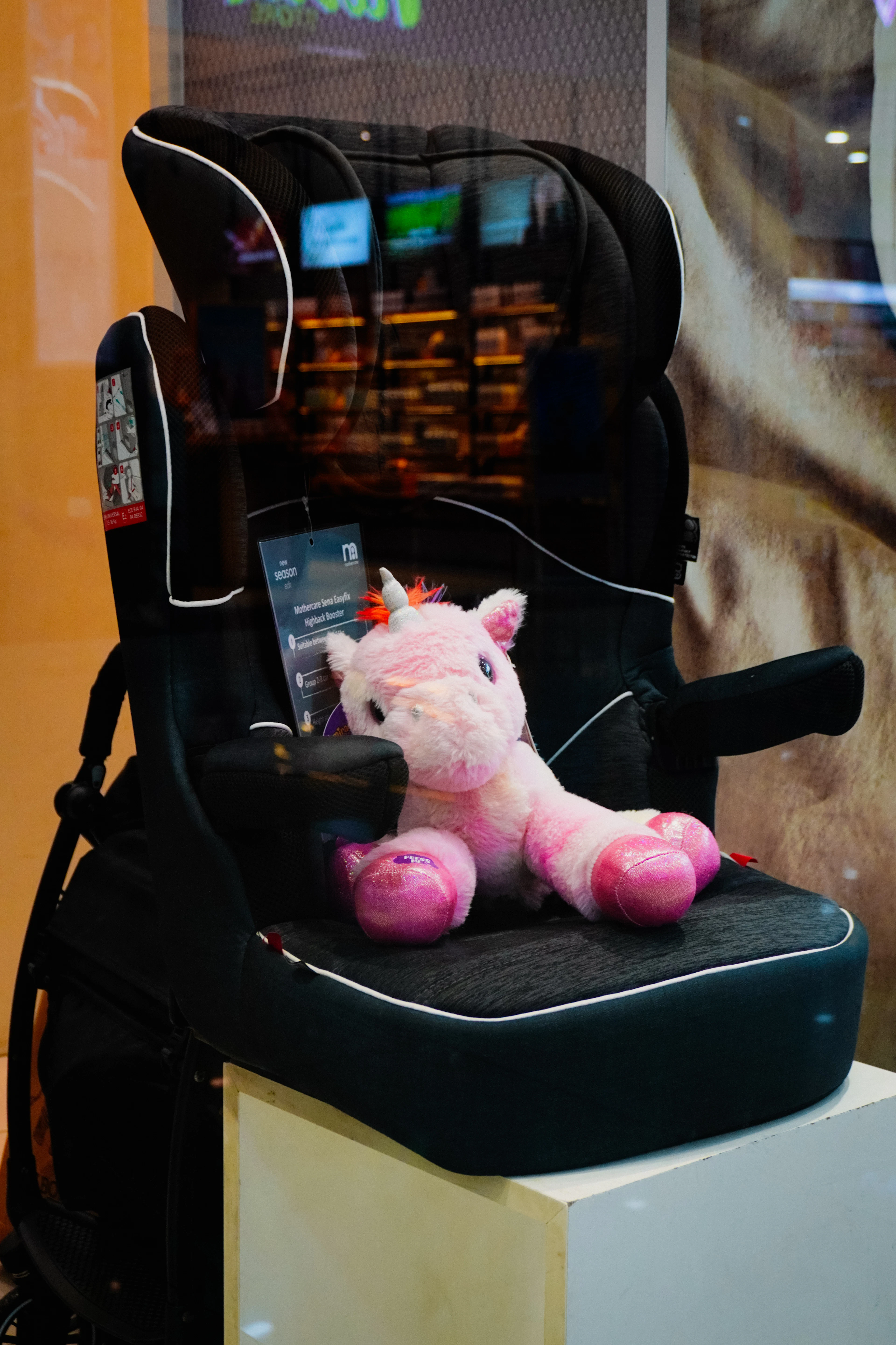 Kinderzitje op de achterbank met een roze knuffeleenhoorn