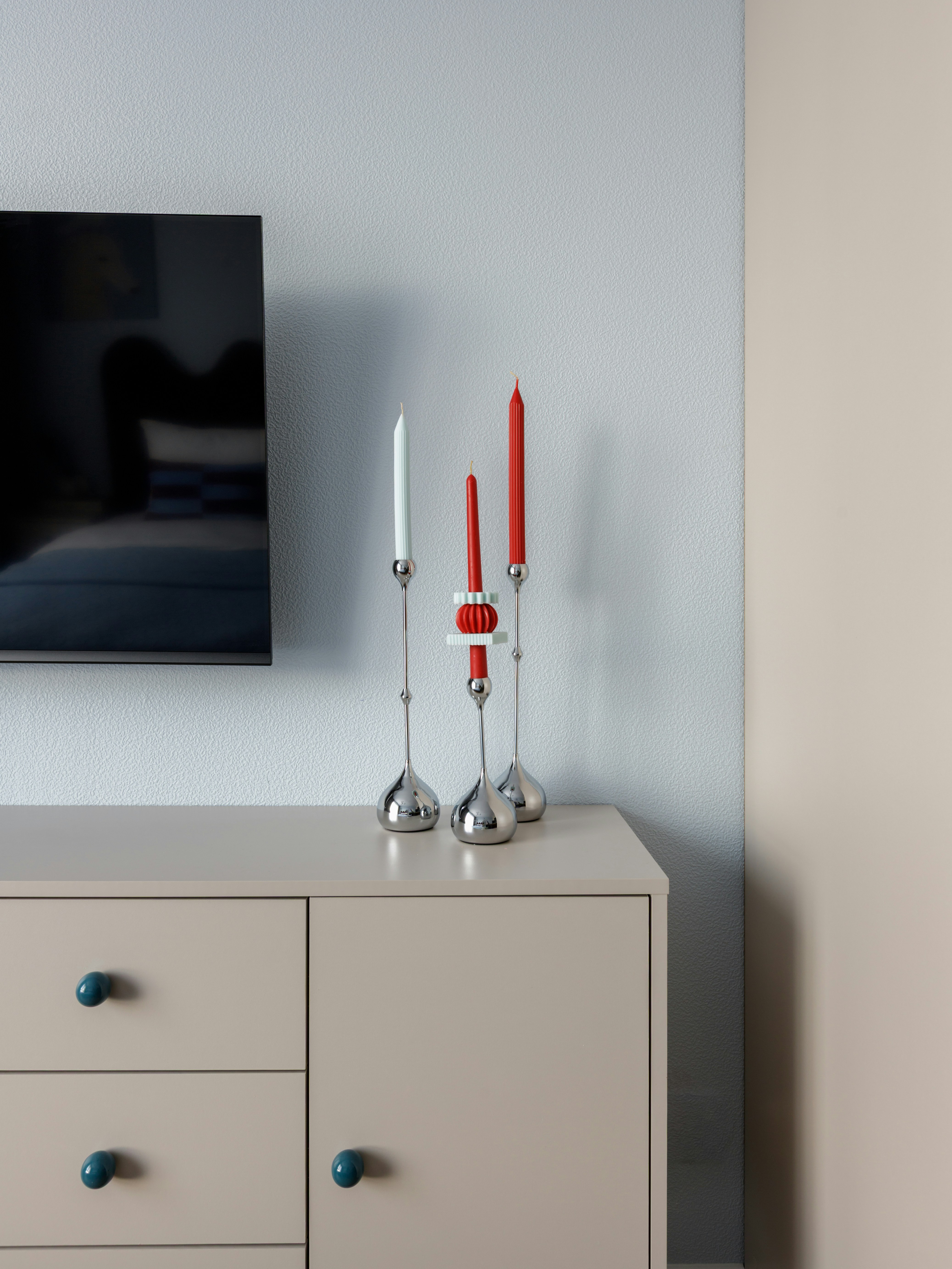Candlesticks with red and white candles on a beige cabinet