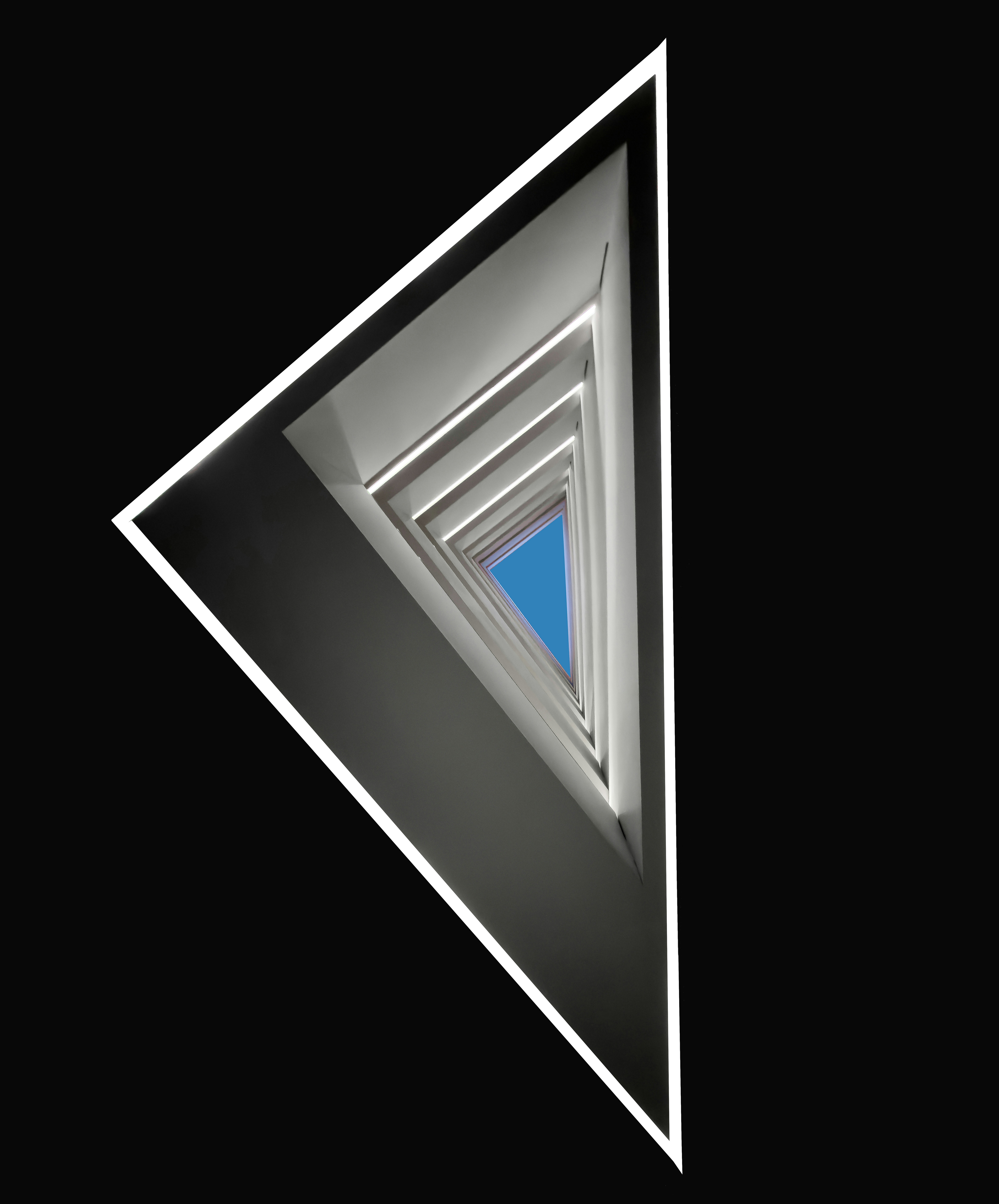 Abstract triangular tunnel with blue sky at the end.