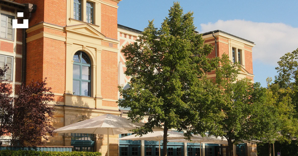 Historic building with outdoor cafe, trees, and benches. photo – Free ...