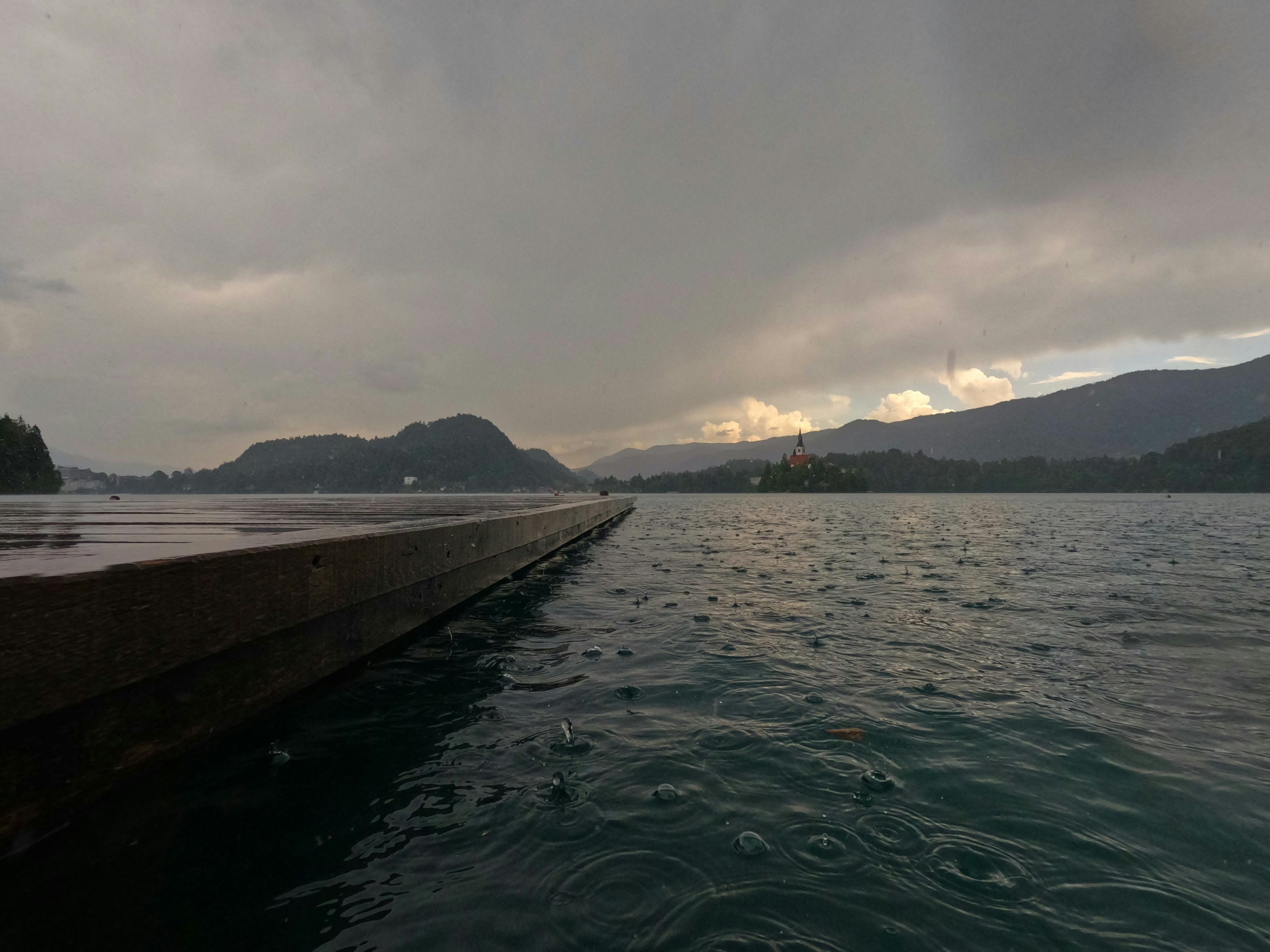 Raindrops on a lake surface with a pier and mountains