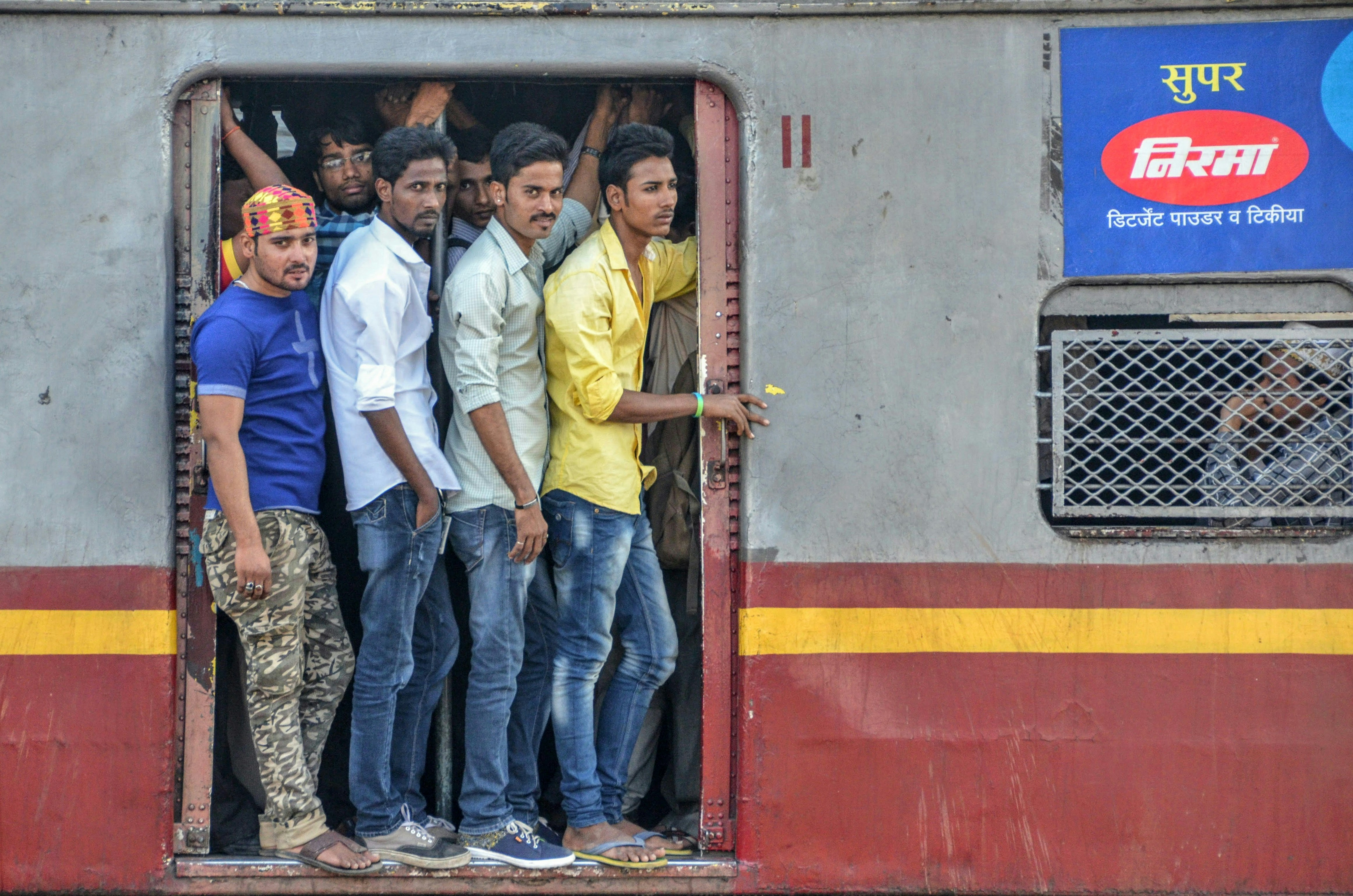 Commuters stand in the open doorway of a crowded train.