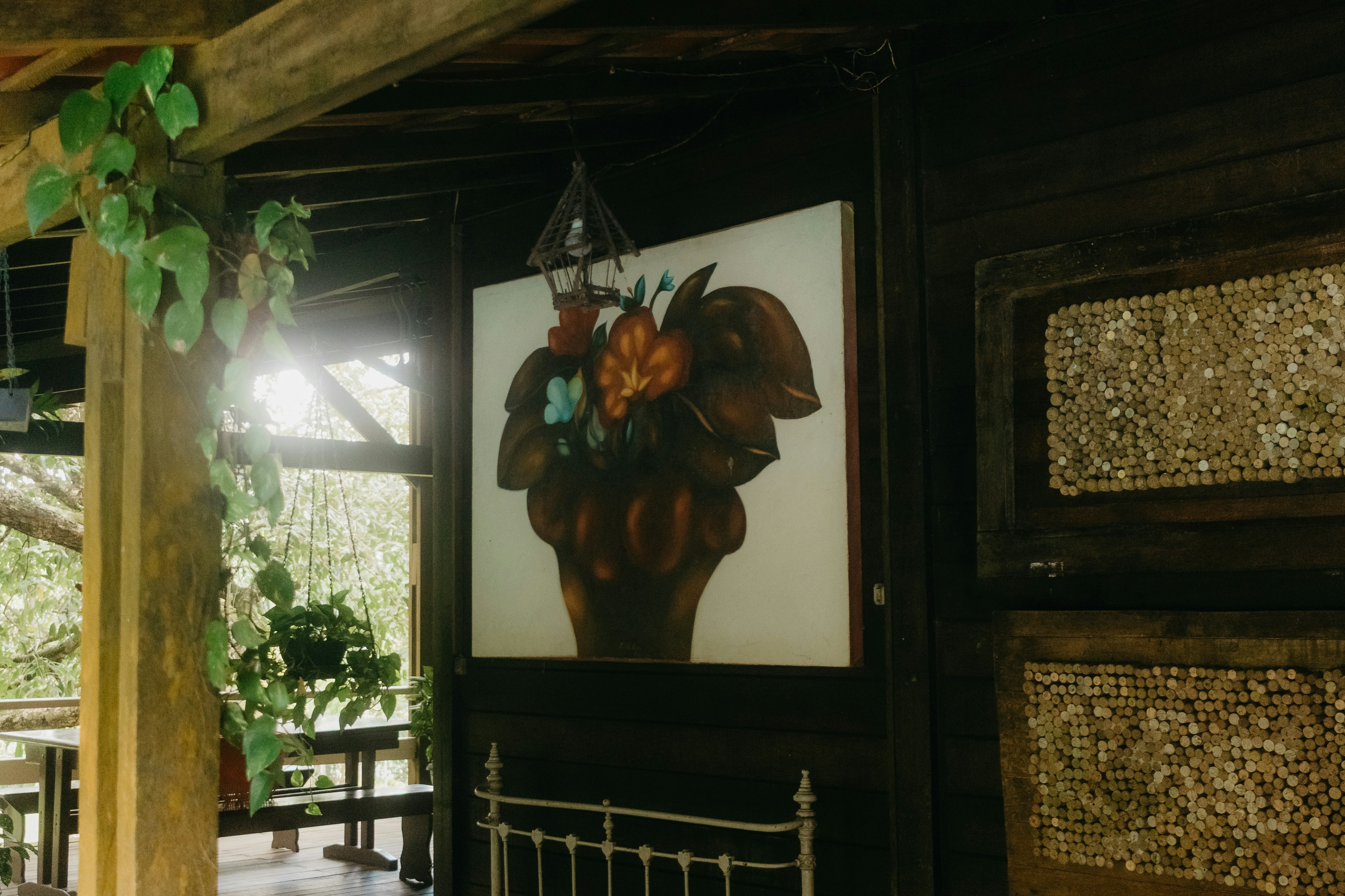Floral painting on dark wood wall with greenery