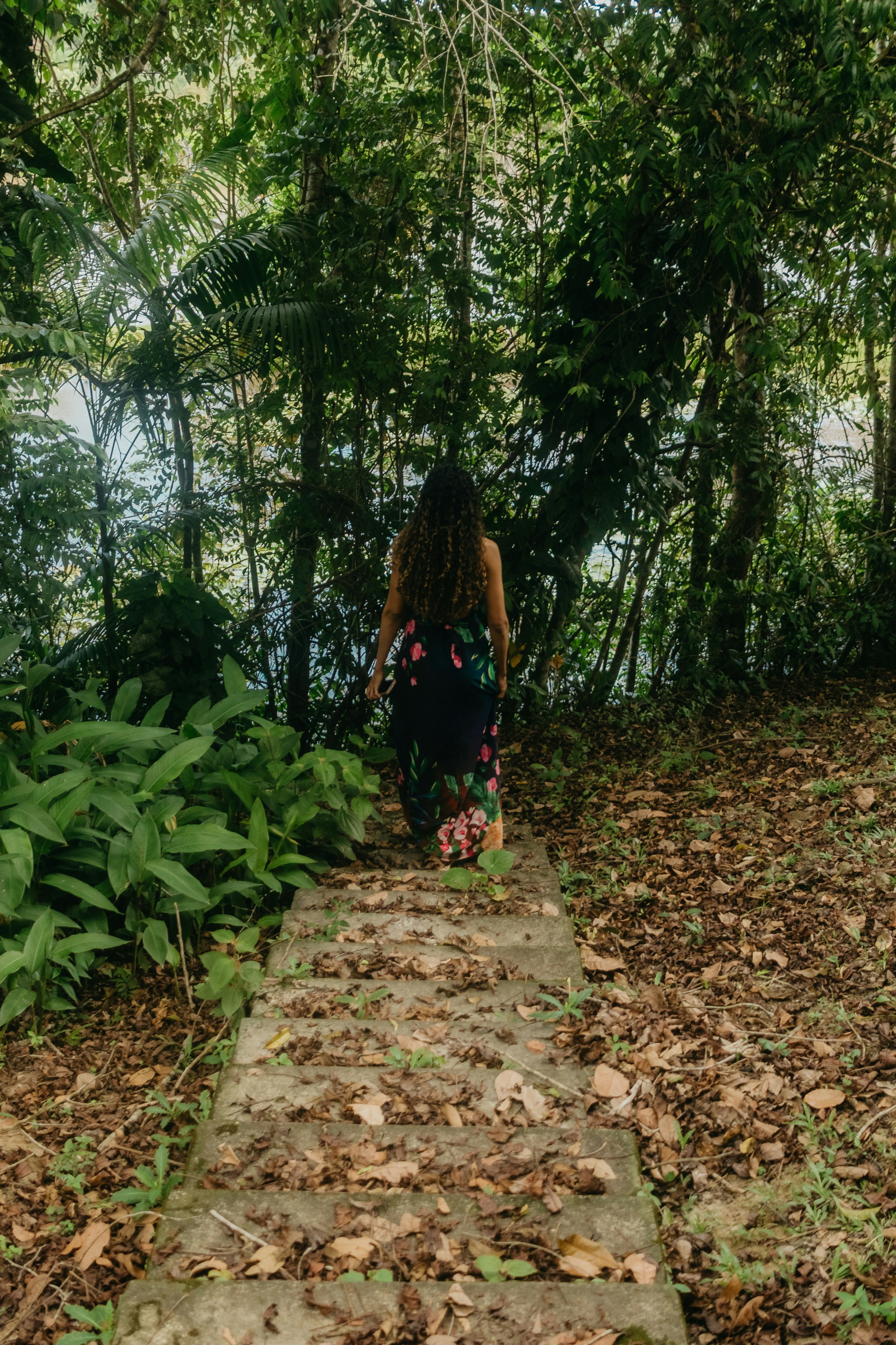 Woman walking down leaf-covered steps in lush forest