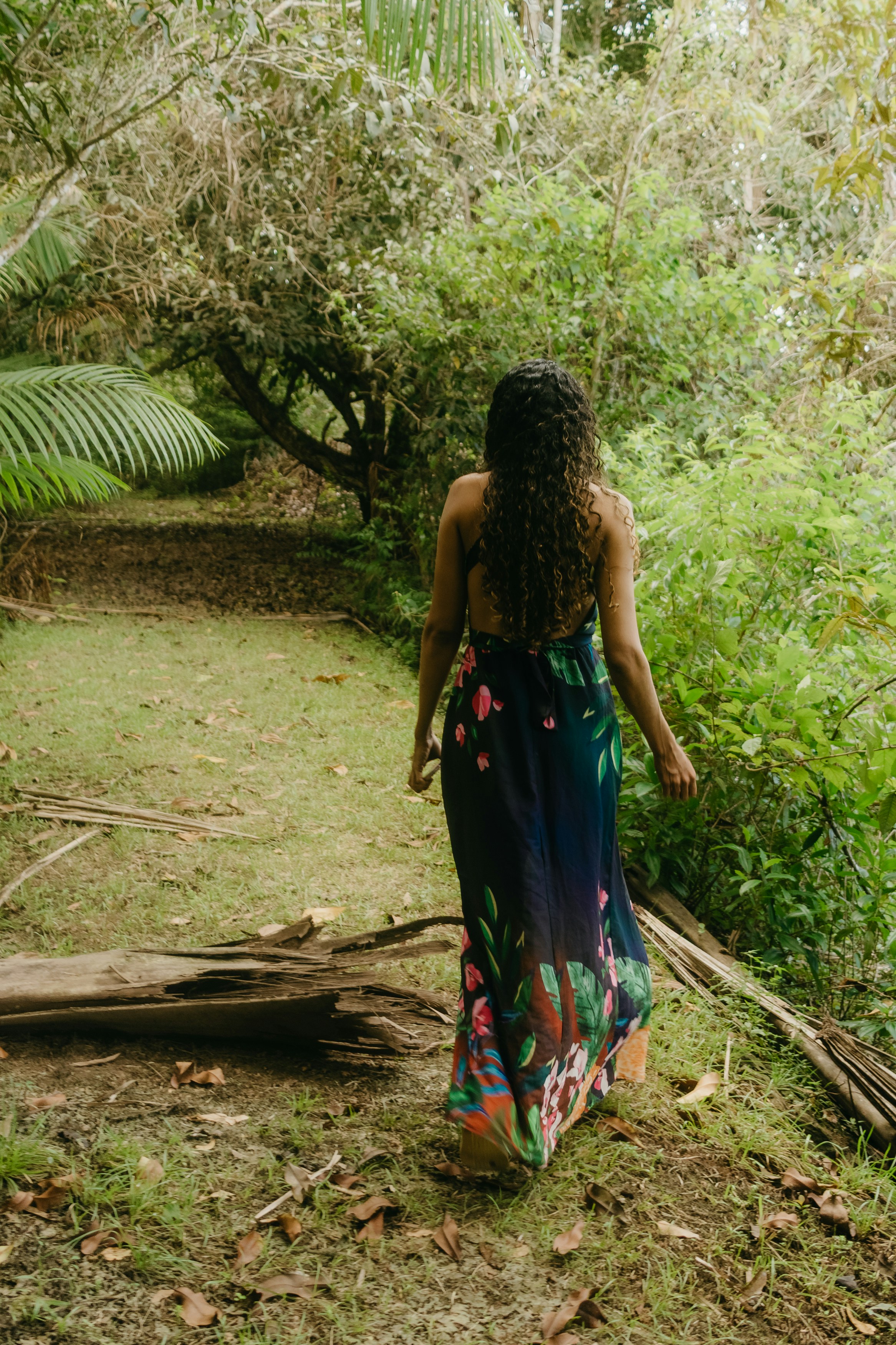 Woman in floral dress walking through a tropical forest