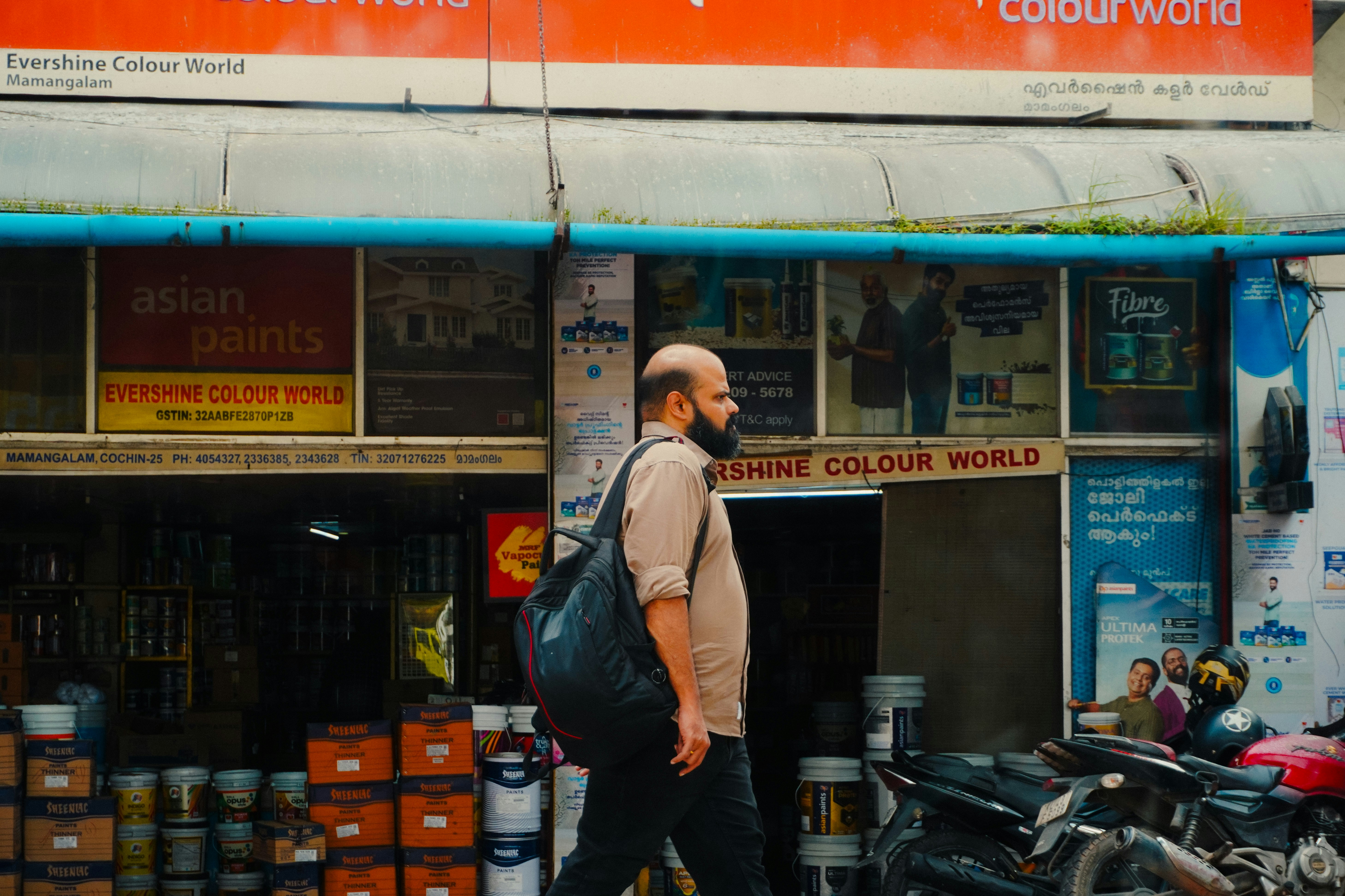 A man walks past a storefront with paint cans.
