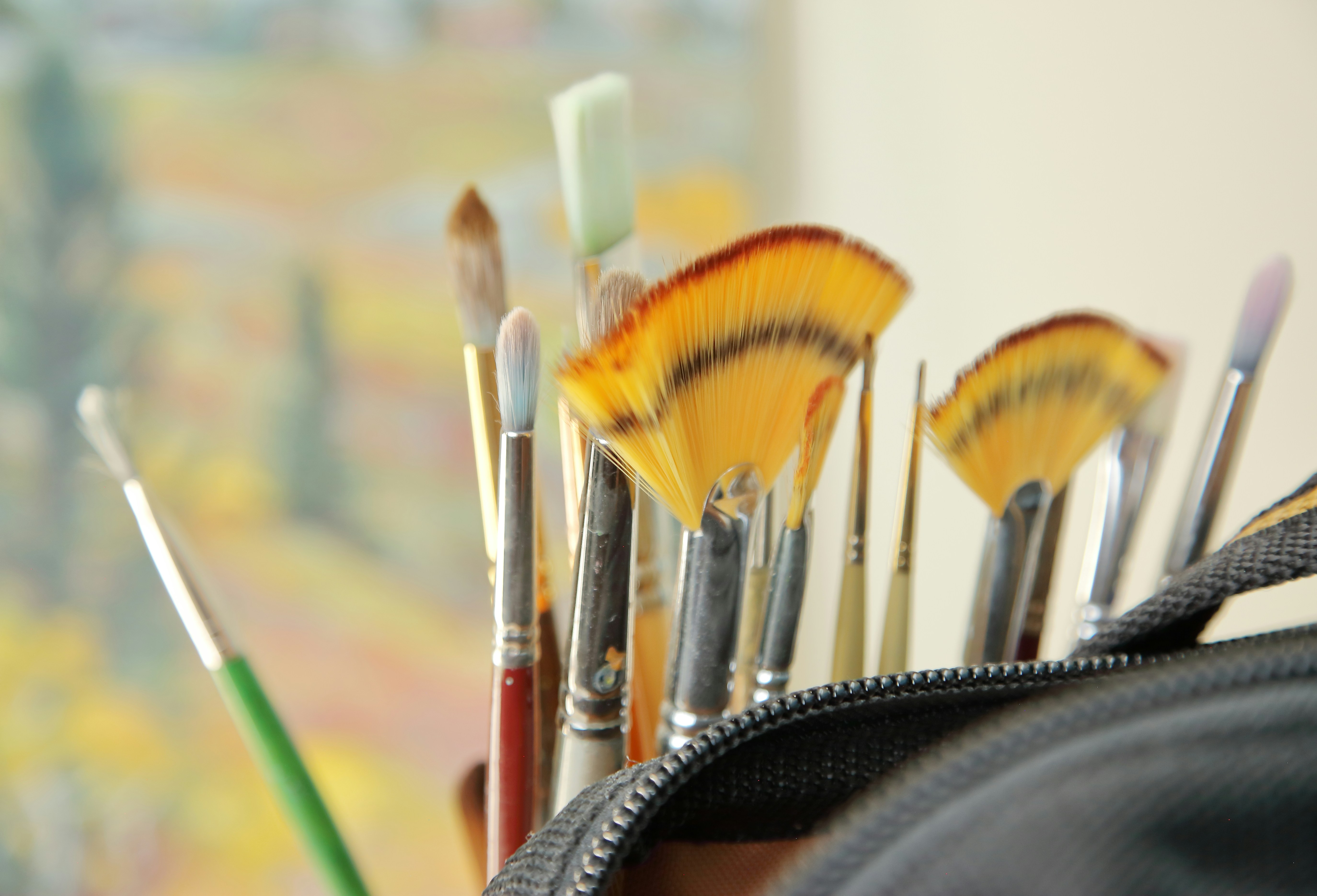 Various artist's paintbrushes, including fan brushes, in a holder.