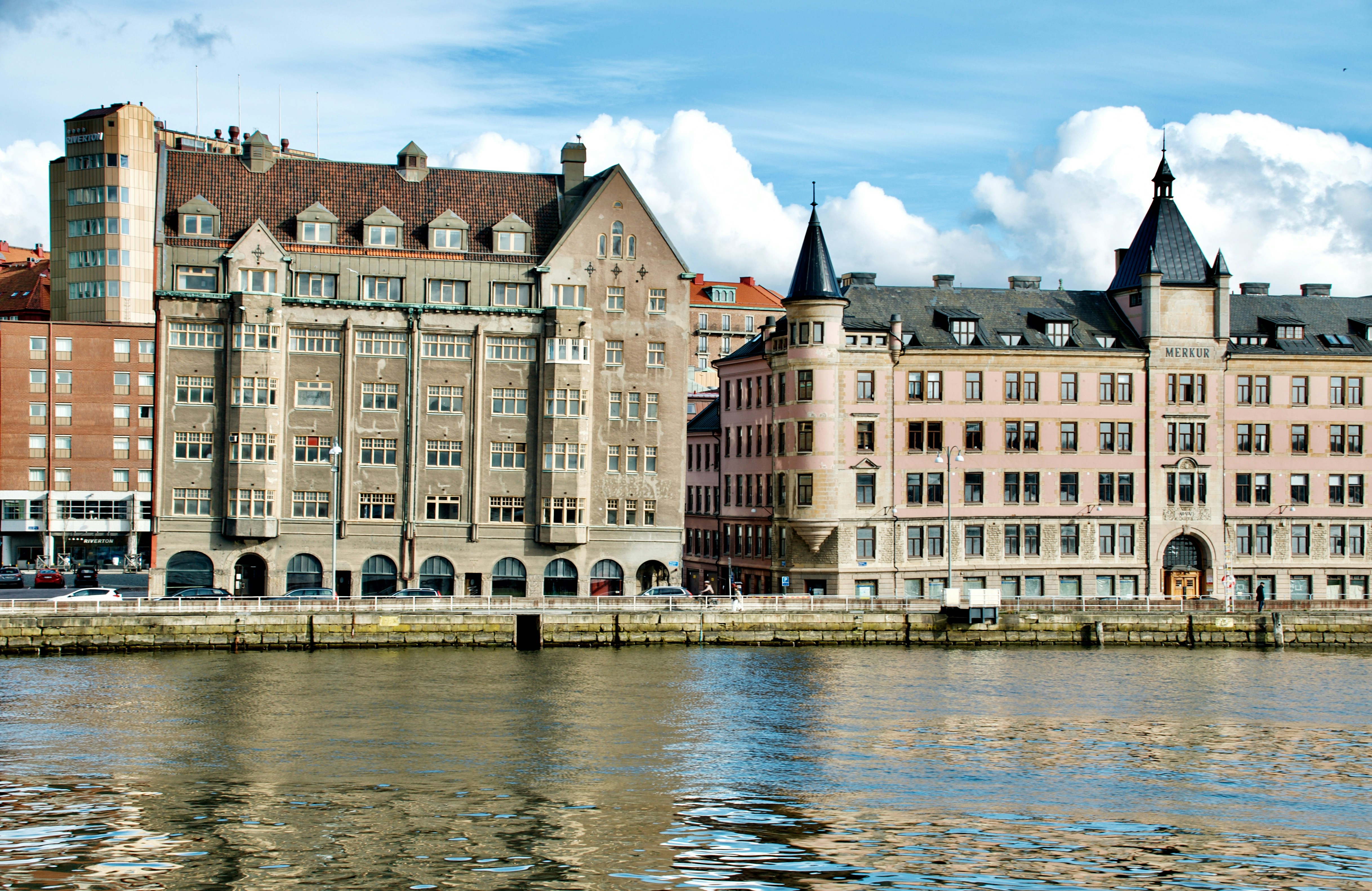 Historic buildings line a waterfront under a blue sky.