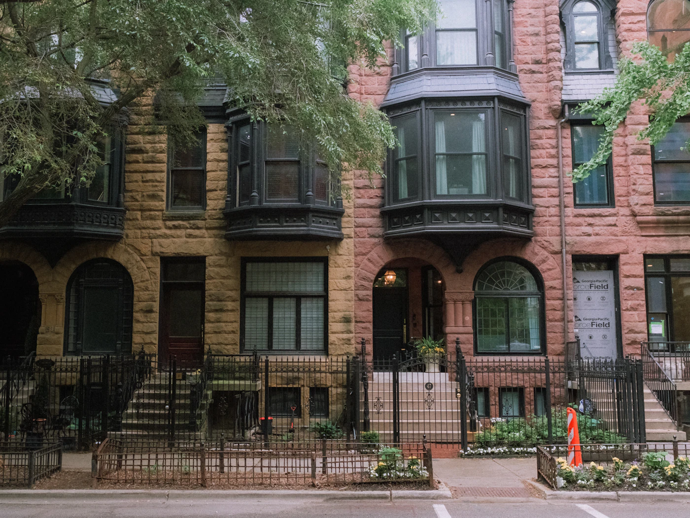 Brick multi-unit row building with bay windows and a front stoop