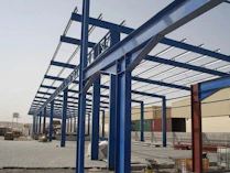 Blue steel framework of a large industrial building under construction.