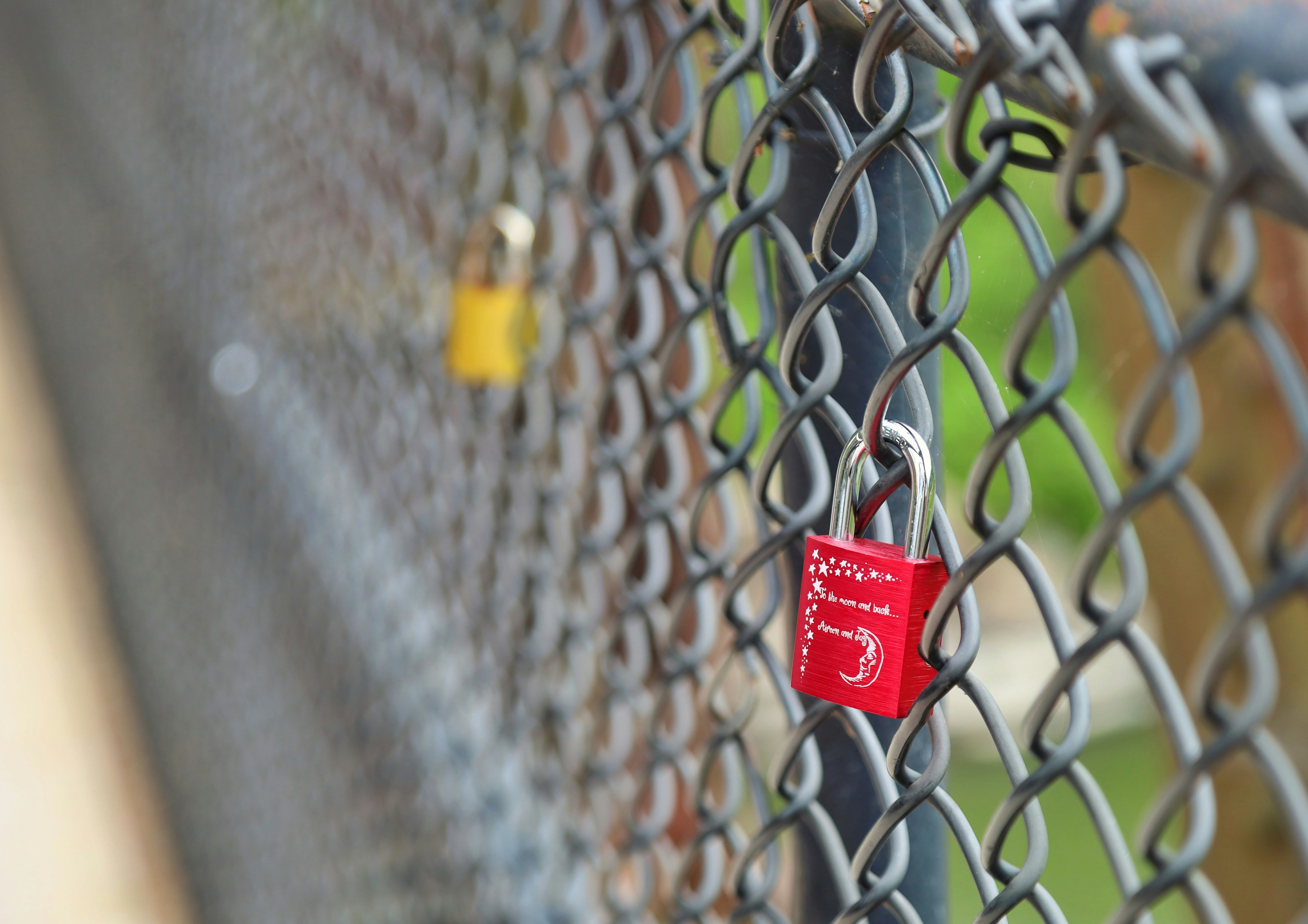 Cadenas rouges et jaunes sur une clôture en grillage.
