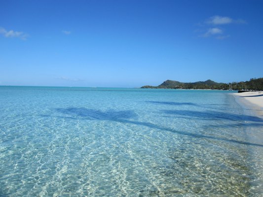 Serene turquoise ocean and white sandy beach with distant hills — Tahiti & Bora Bora, French Polynesia