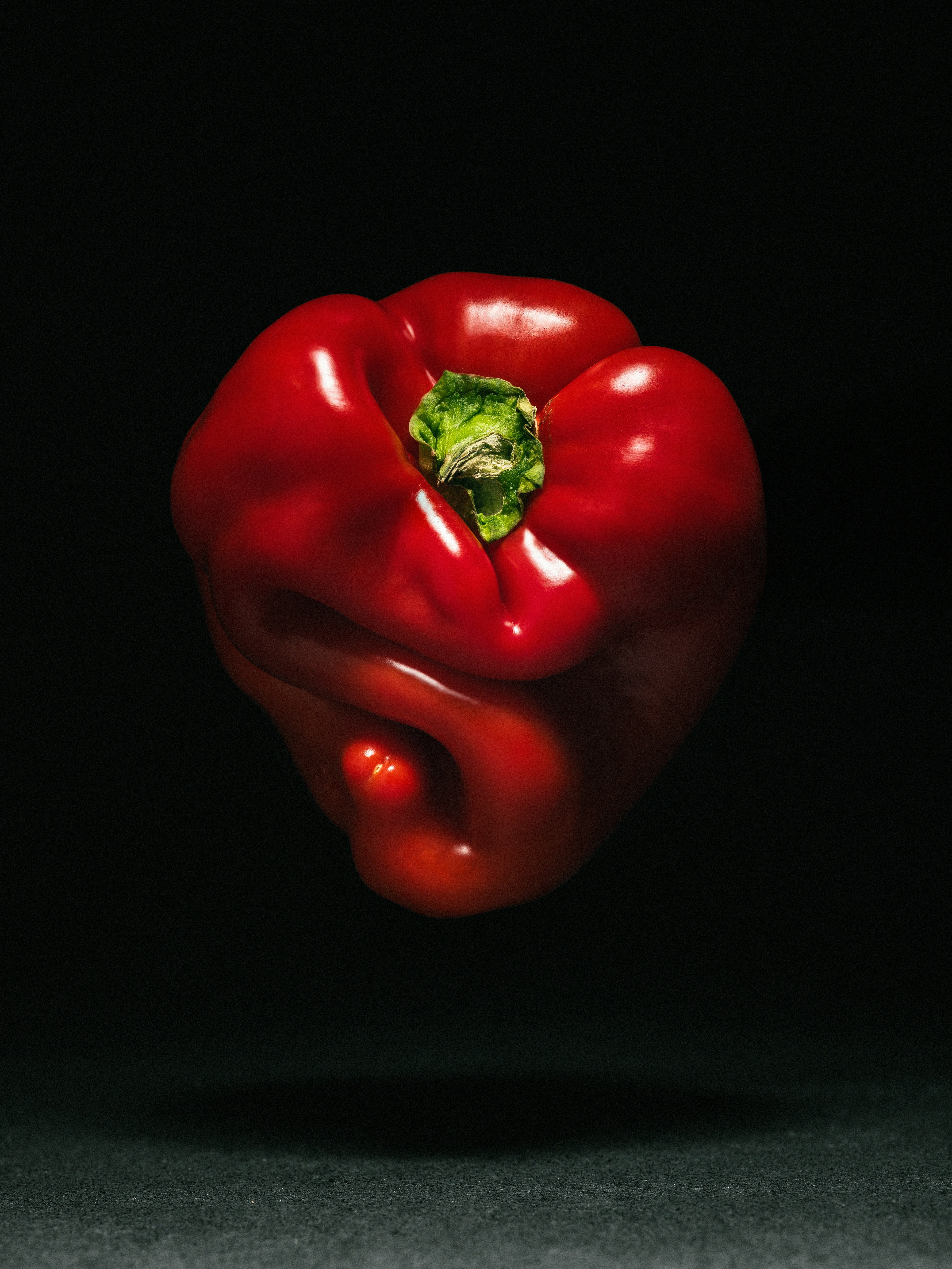 A vibrant red bell pepper floating against a dark background.