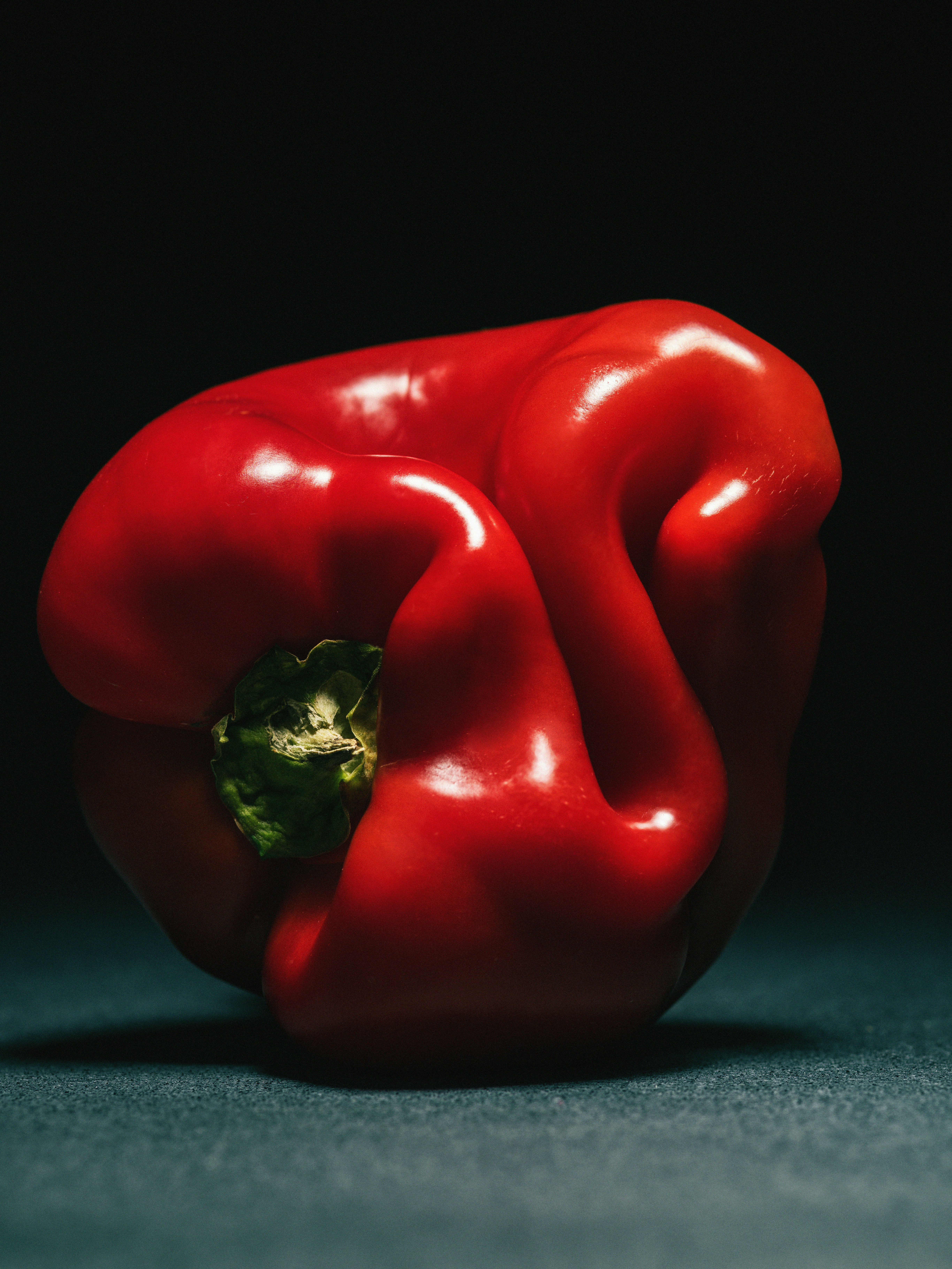 A vibrant red bell pepper on a dark background.