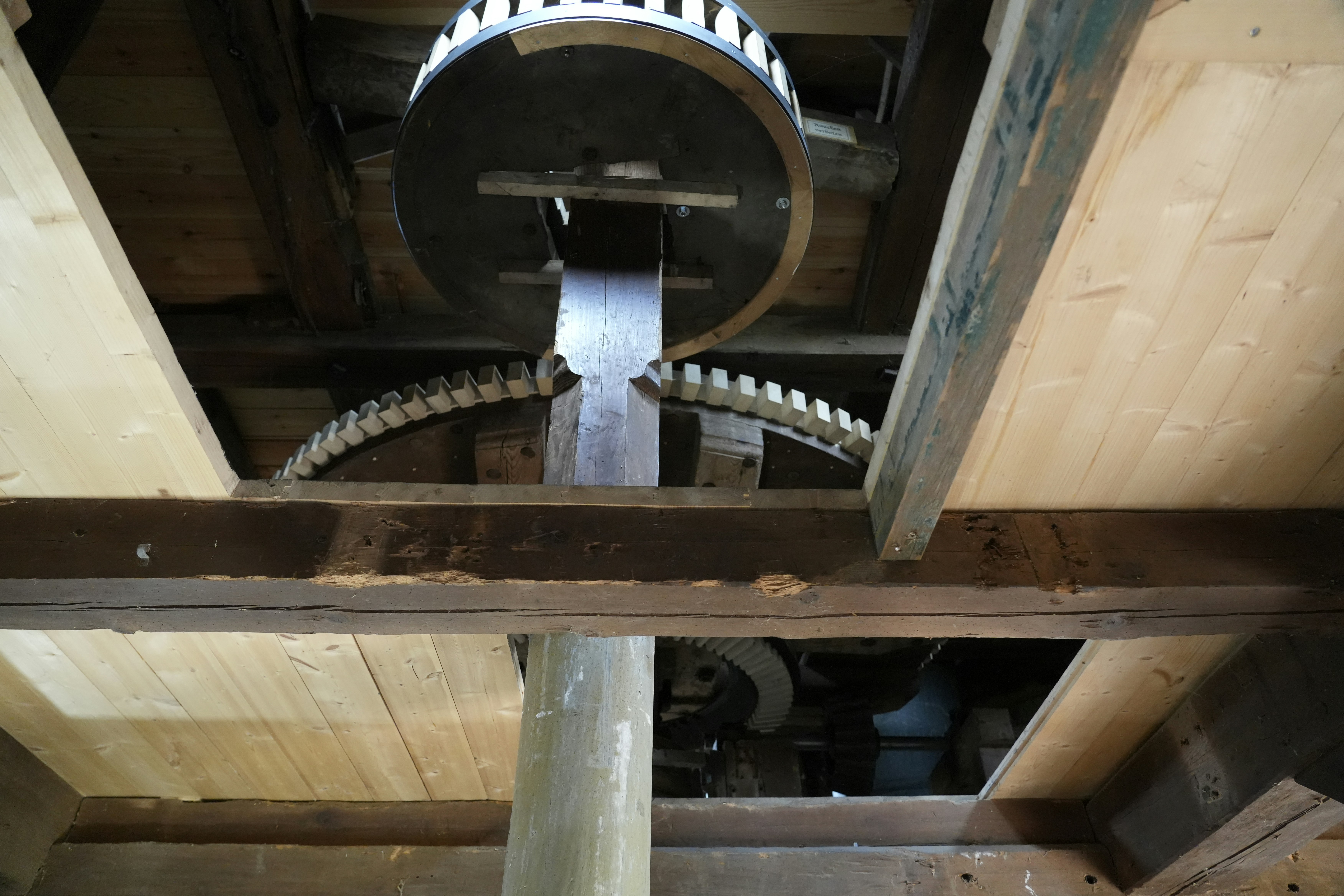Rustic wooden gears and shaft inside a traditional mill.